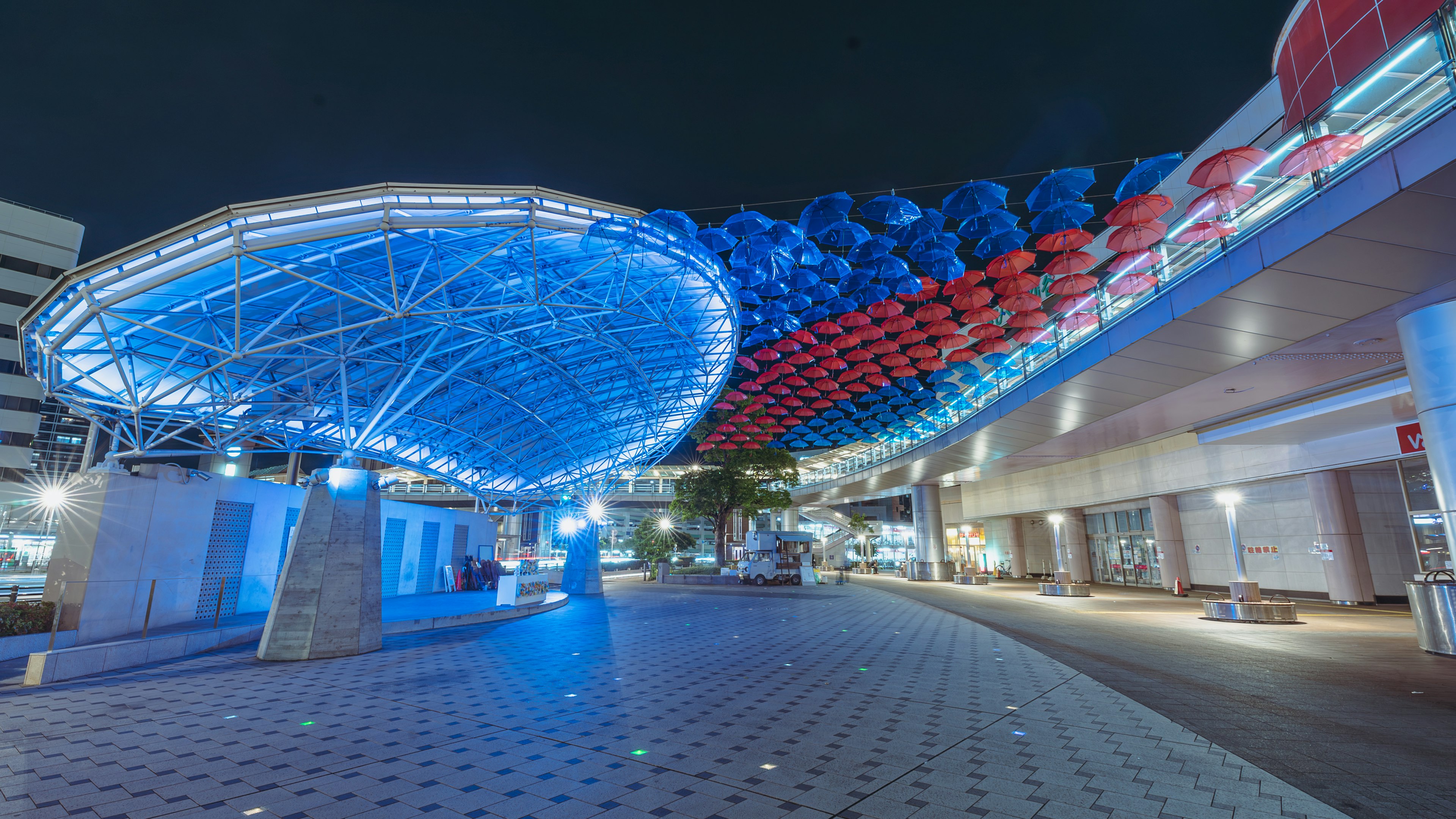 Struktur arsitektur modern yang diterangi biru dan merah di malam hari