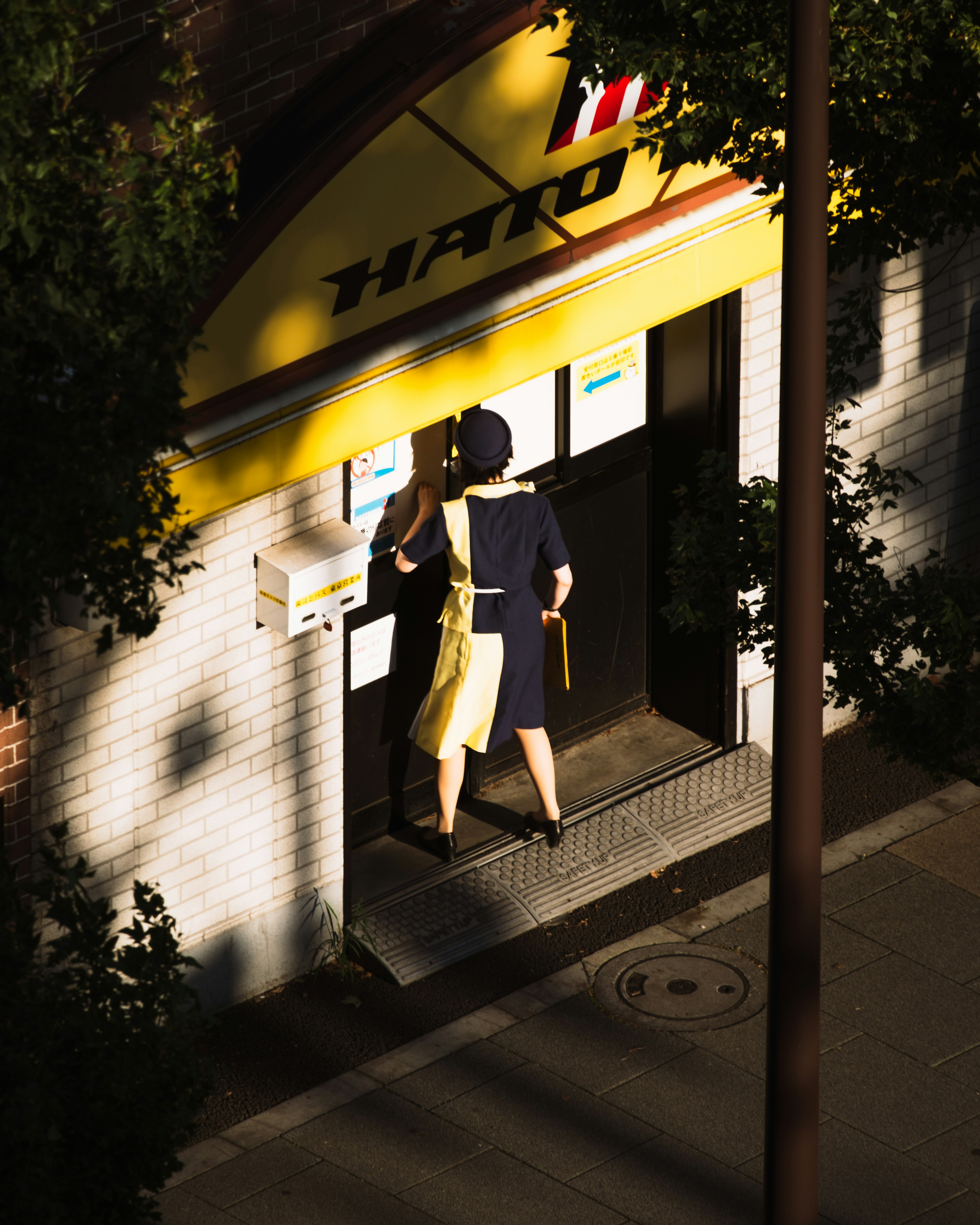 A figure standing in front of a building with a yellow sign