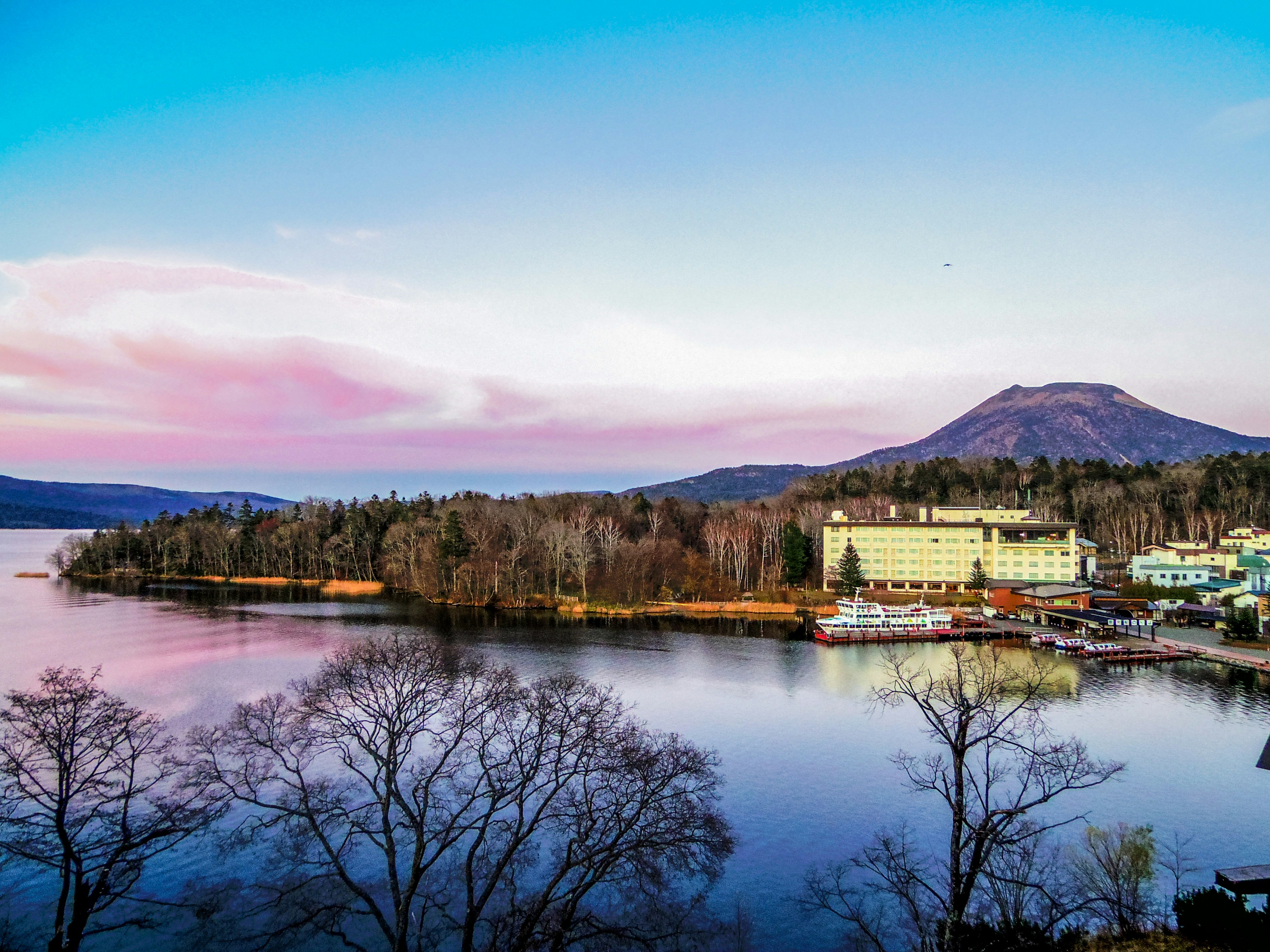 Scenic view of a lake with a resort hotel and mountains in the background