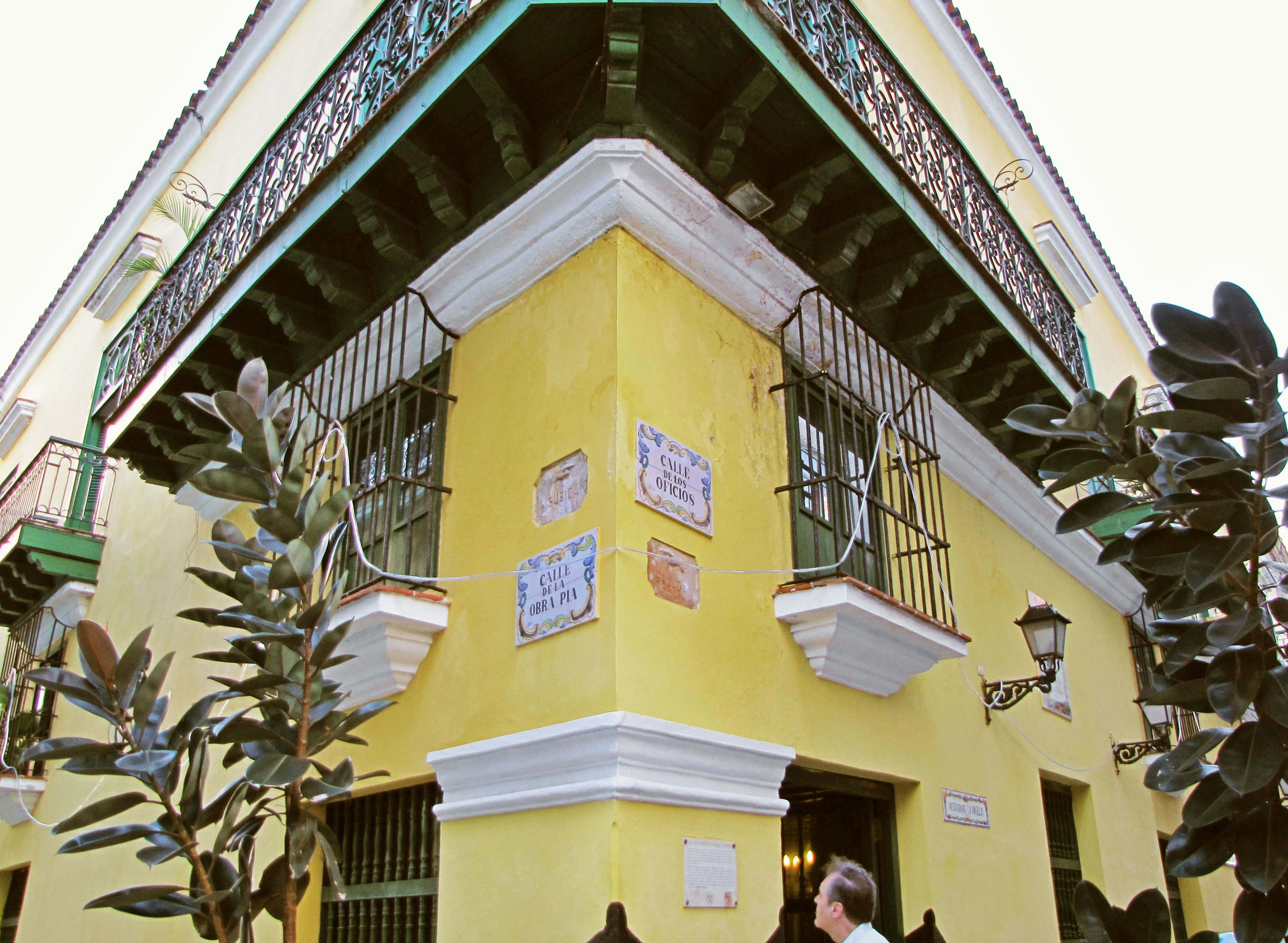 Corner view of a building with yellow walls and green balcony