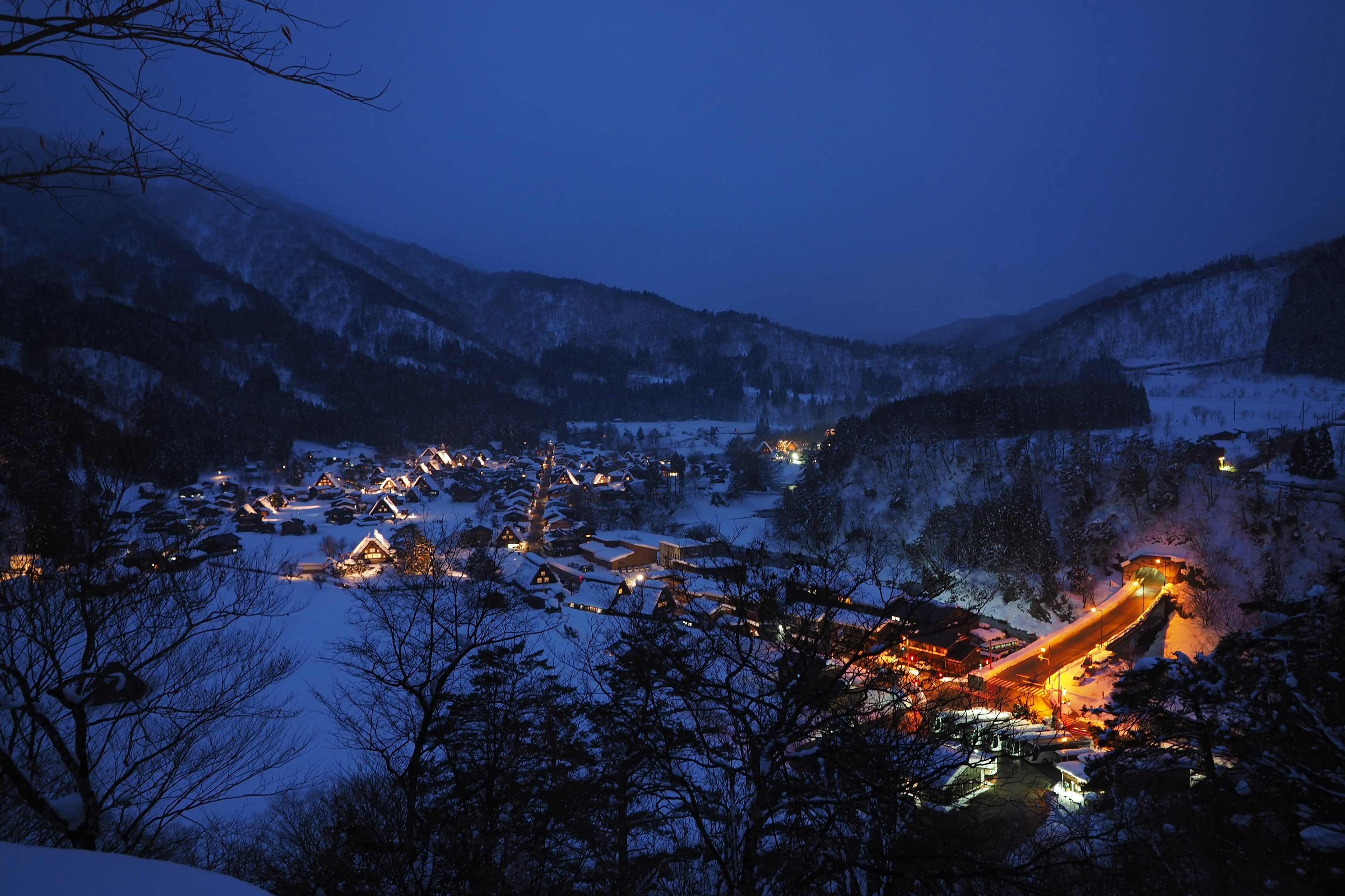 Villaggio innevato di notte con luci calde delle case e delle montagne