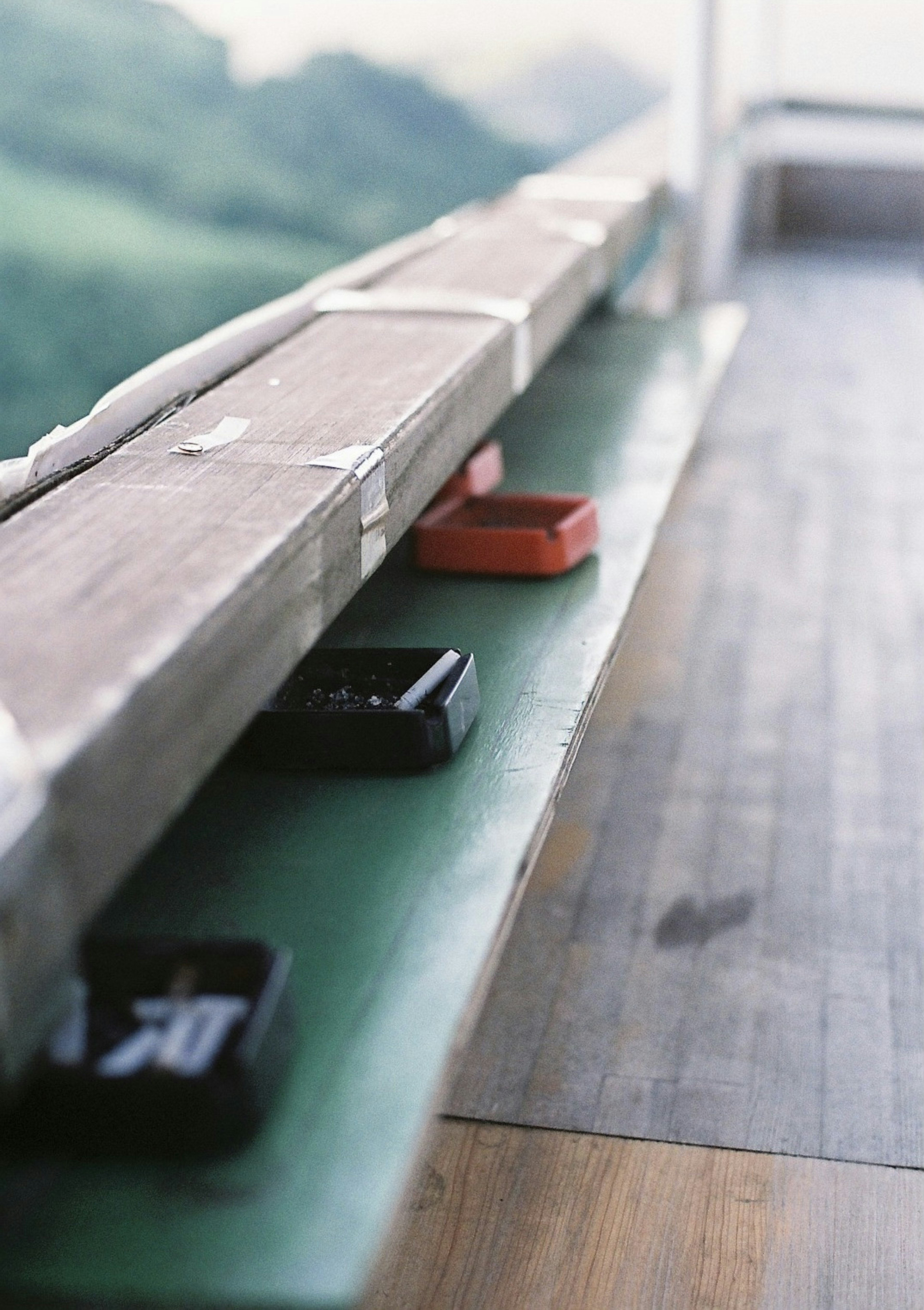 A wooden shelf with black and red boxes featuring a scenic background