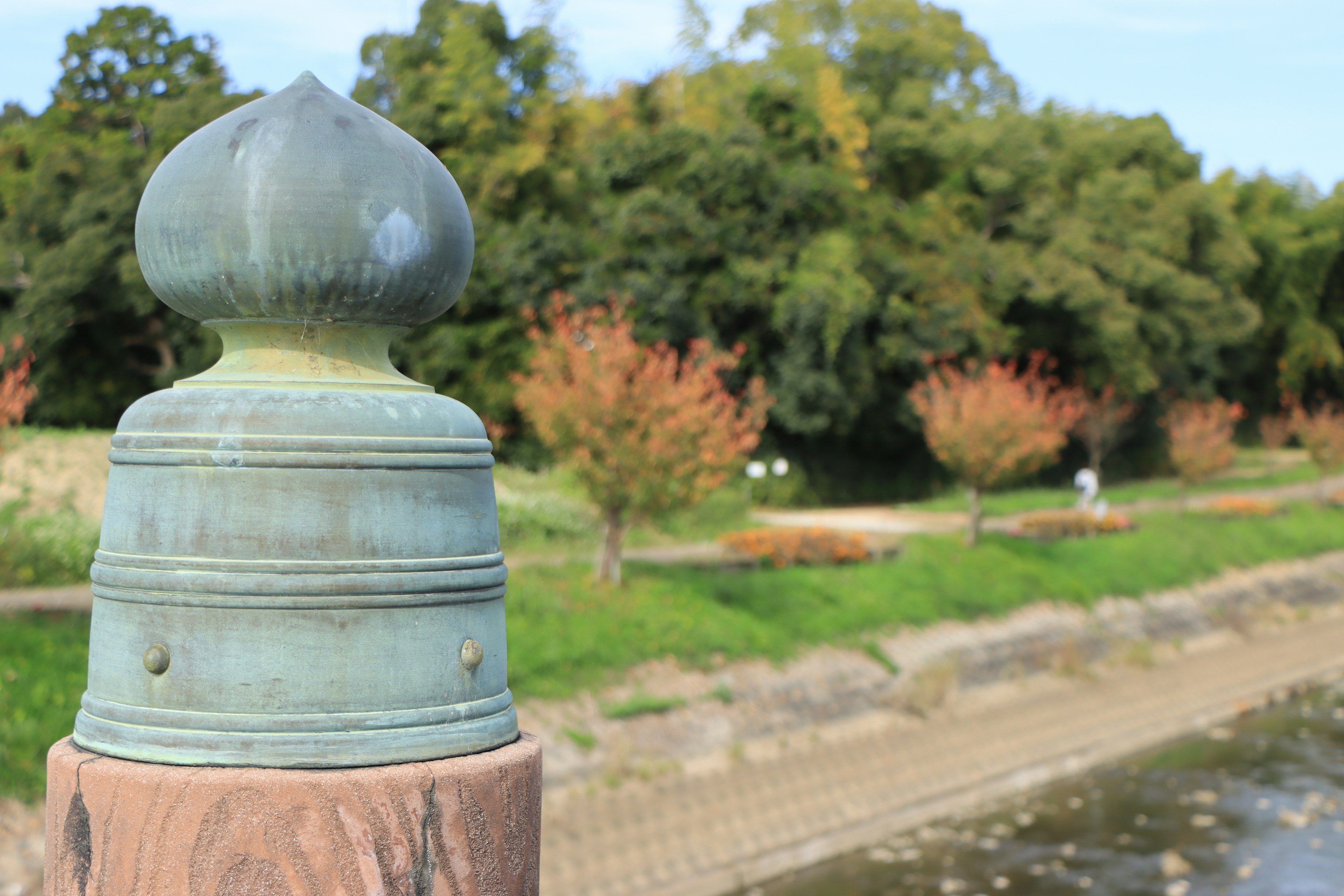 Tête de pilier en bronze décoratif avec un paysage de parc en arrière-plan