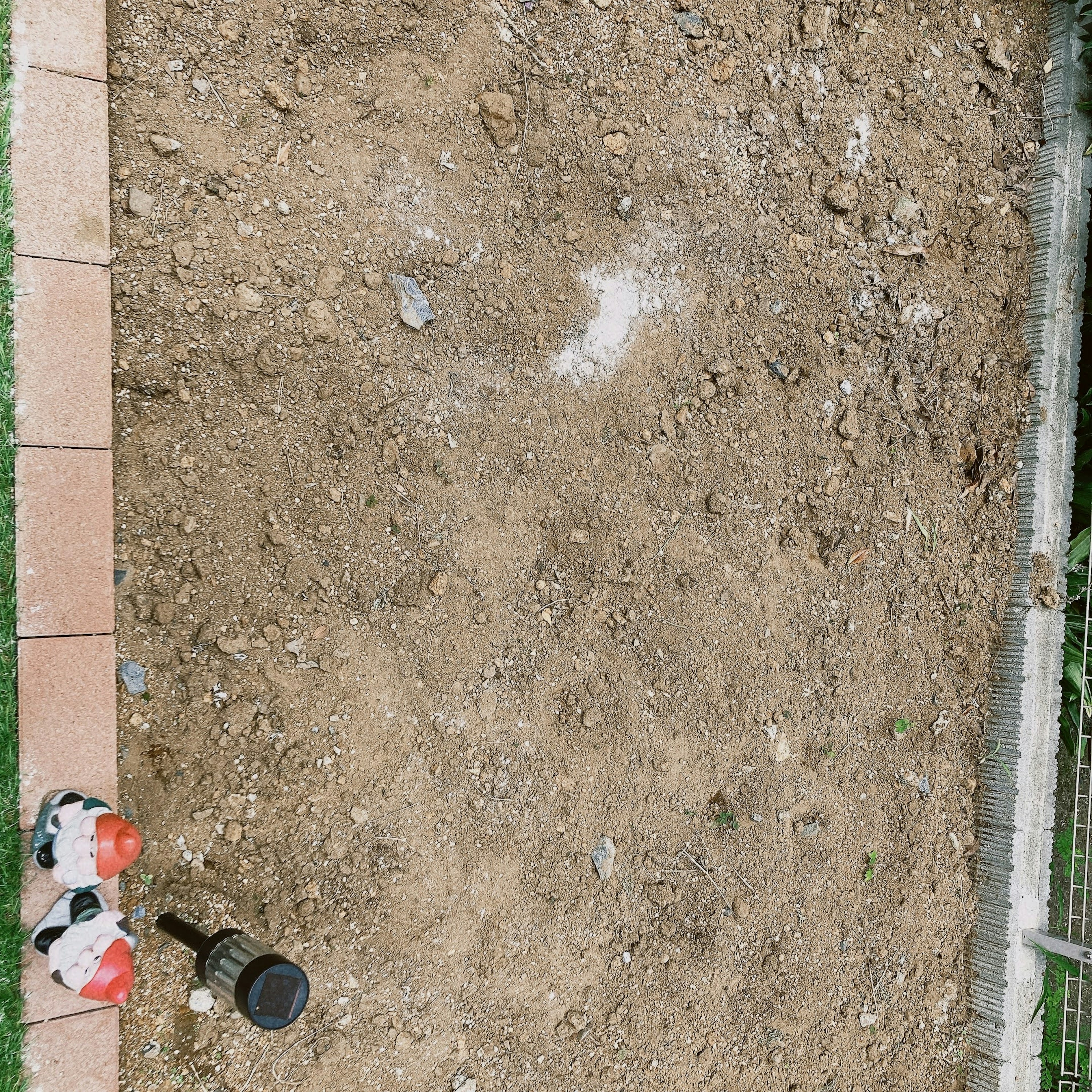 A bare dirt area with soccer ball decorations and a garden light