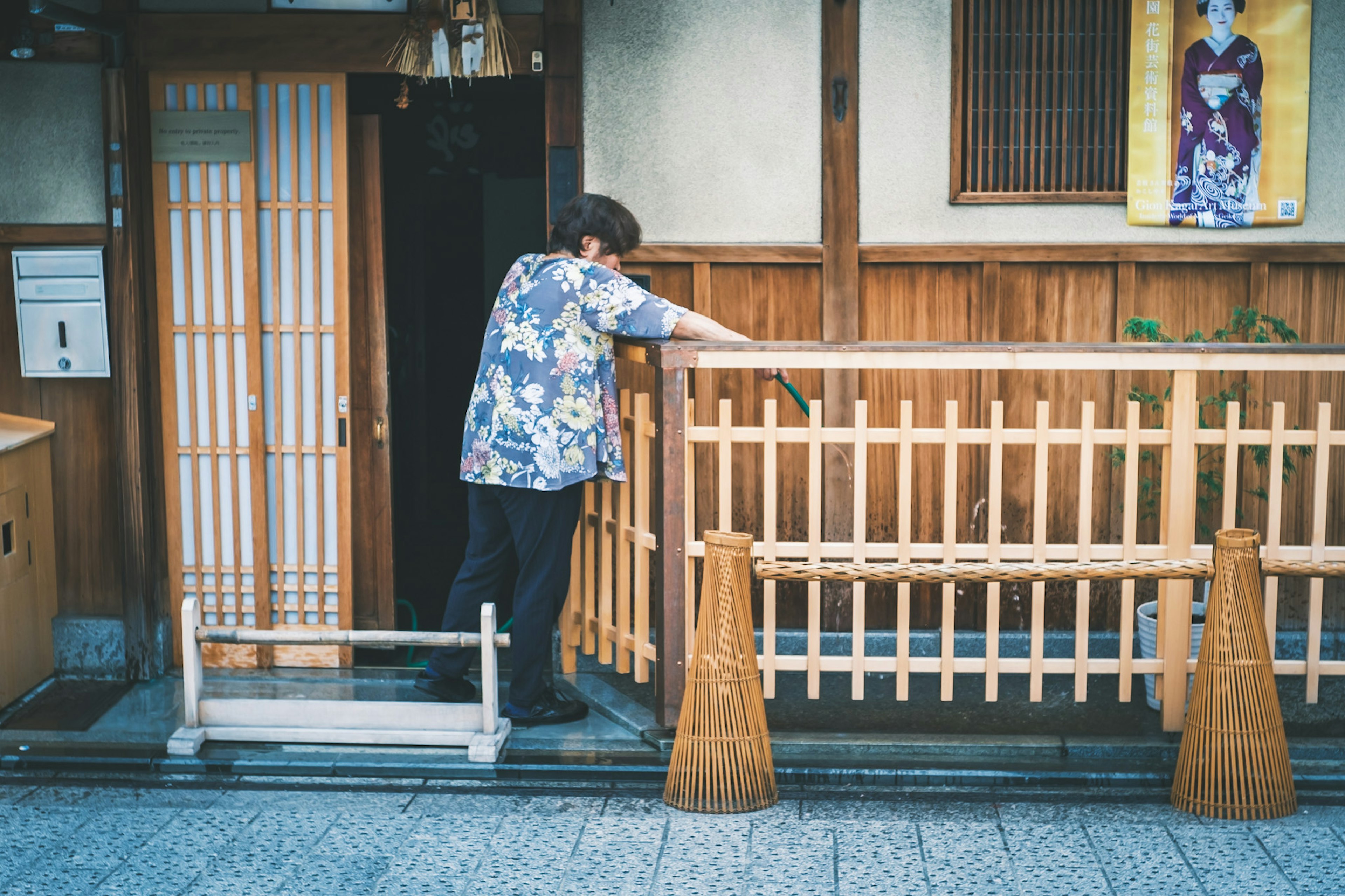 木製の手すりの前で作業をしている男性の姿 花柄のシャツを着ている