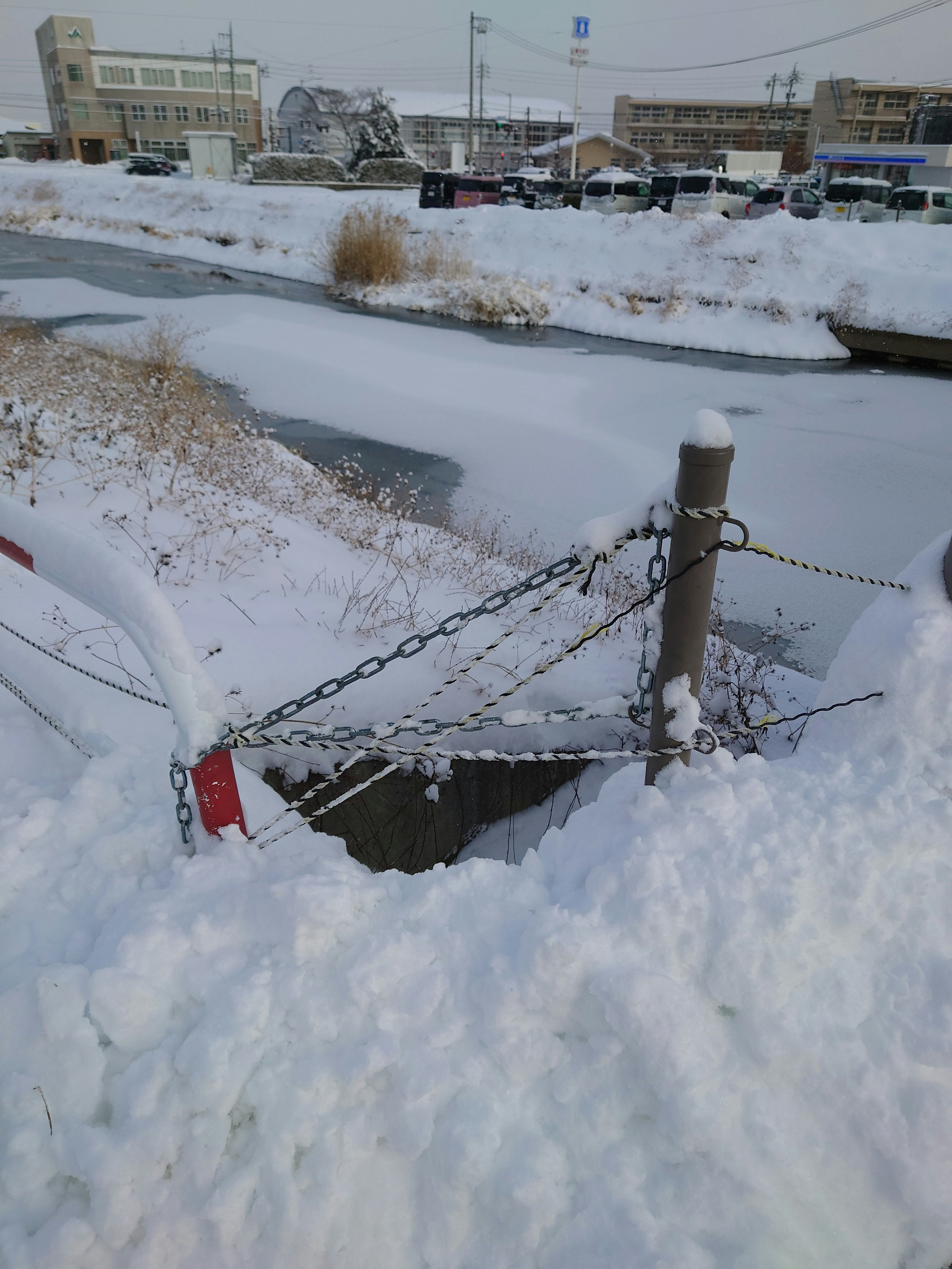 Snow-covered riverbank with a chained pole