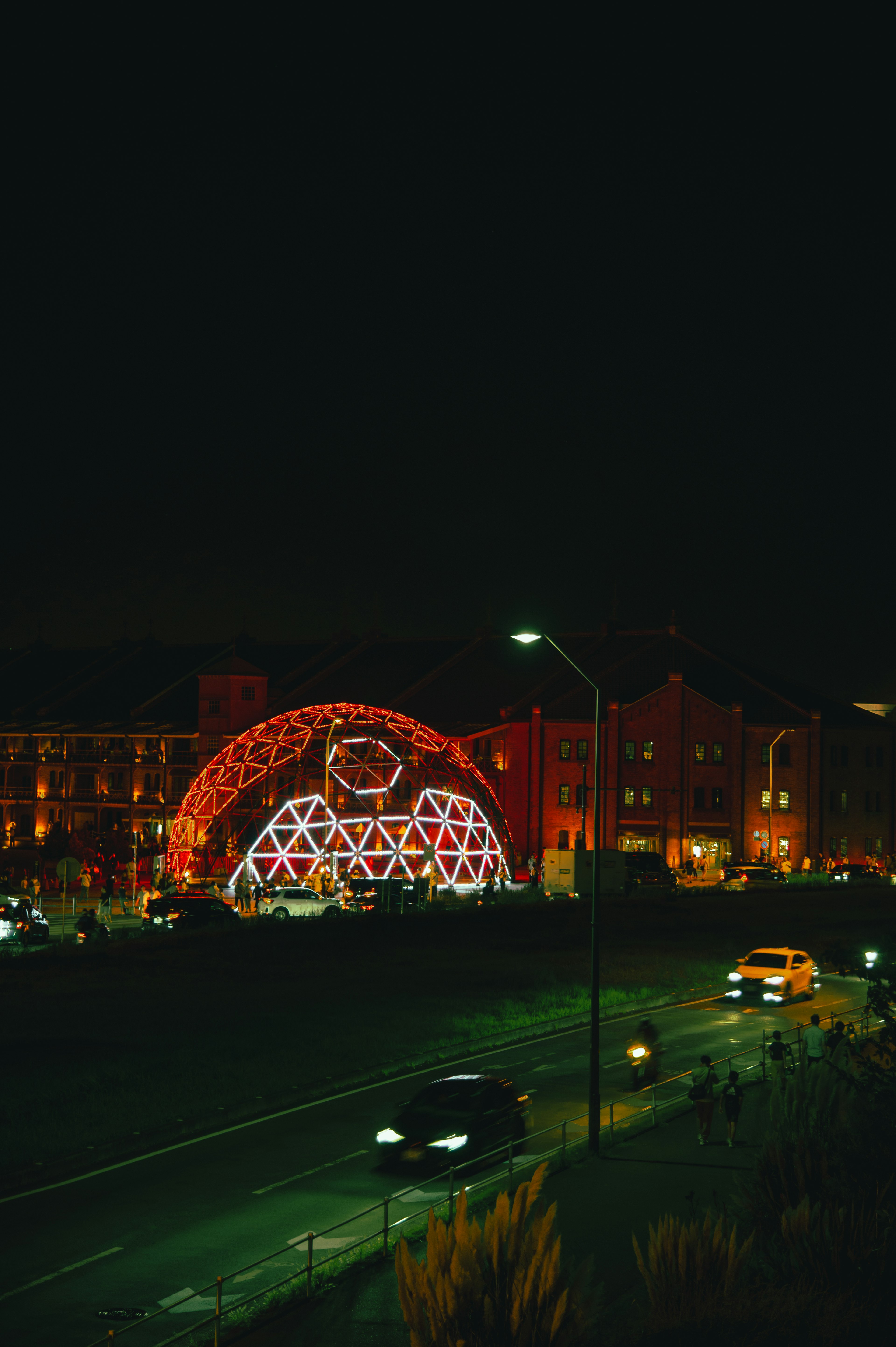 Unique arch-shaped building illuminated in vibrant colors at night