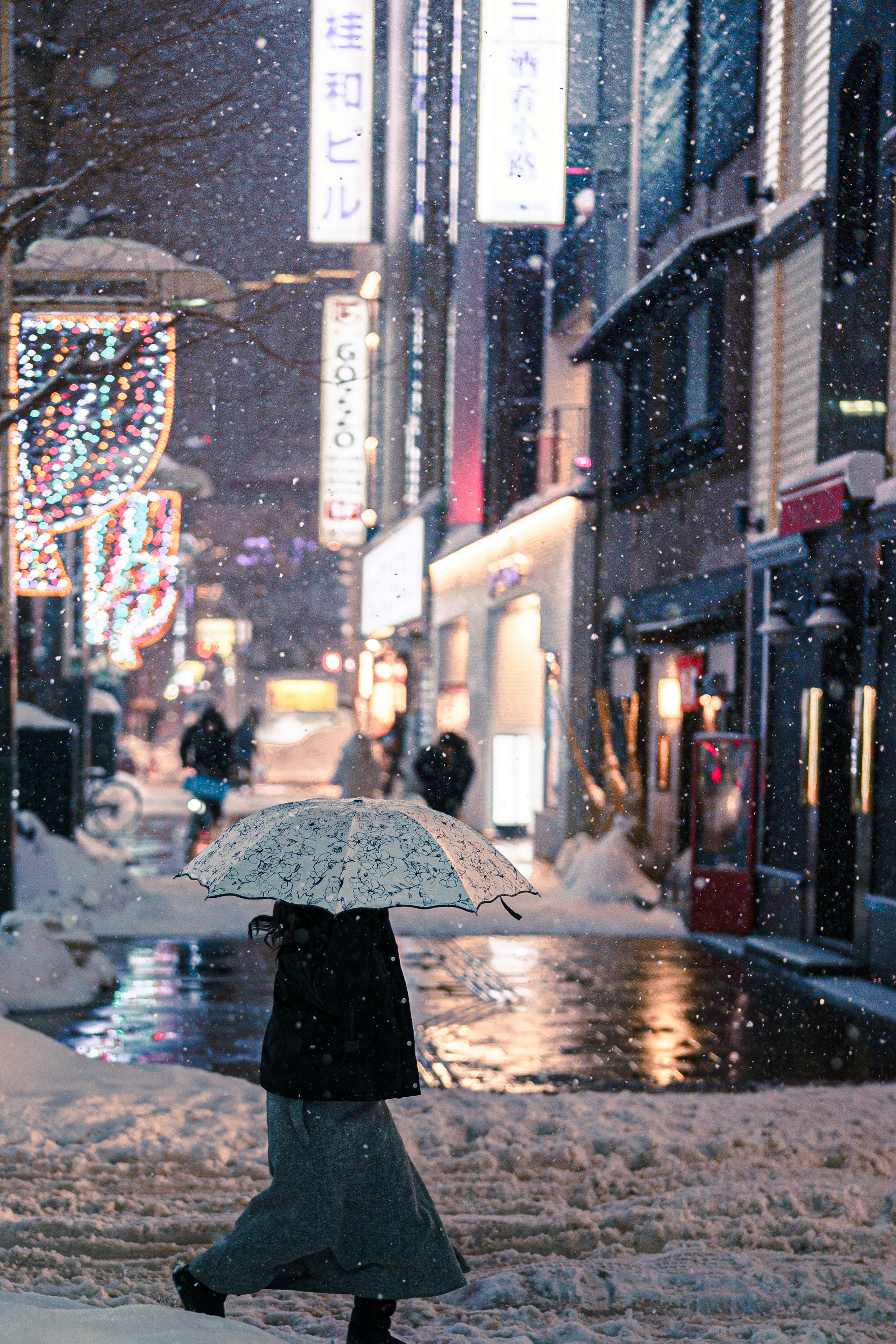 Mujer caminando en una calle nevada de noche con letreros de neón