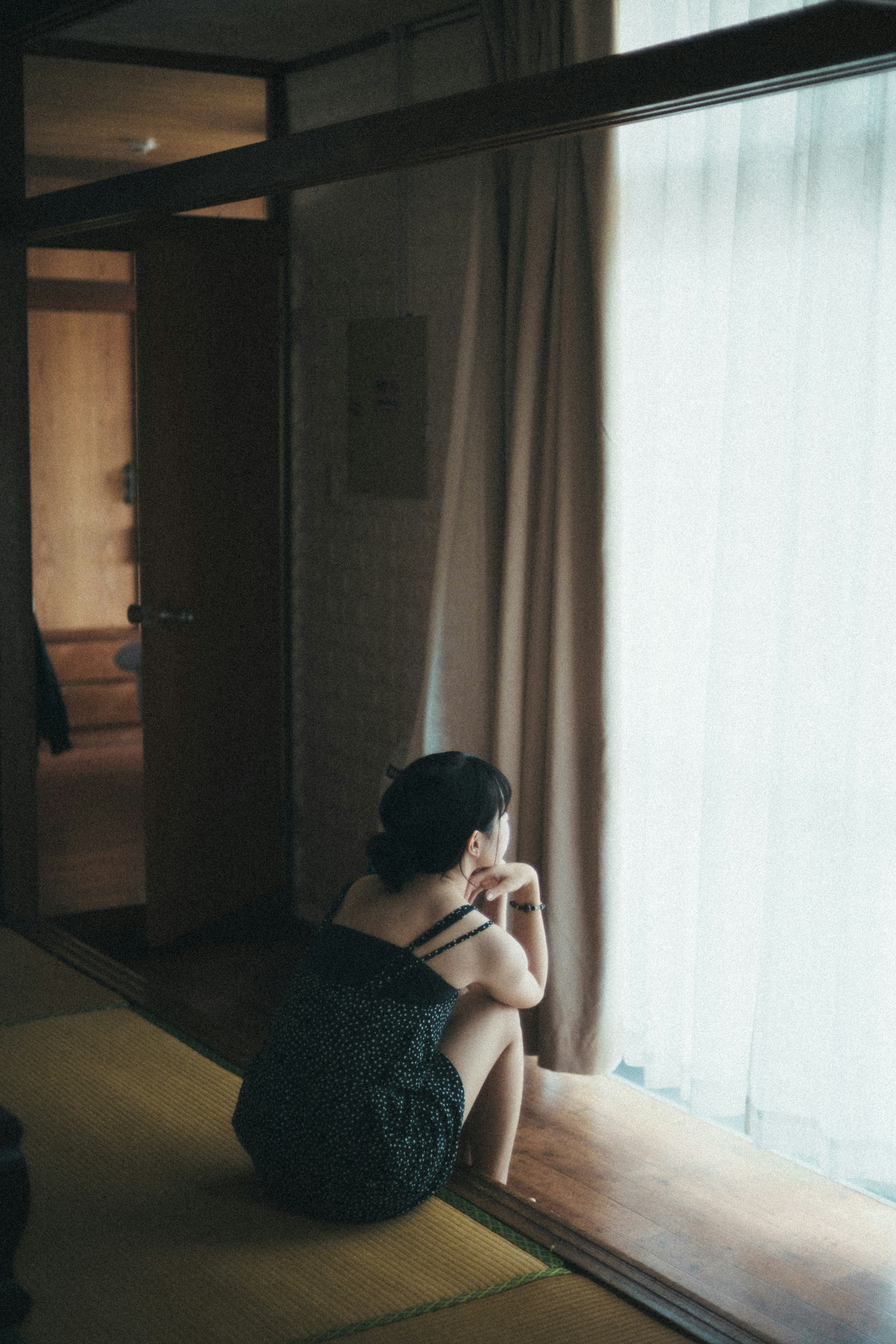 Una mujer sentada junto a la ventana perdida en sus pensamientos