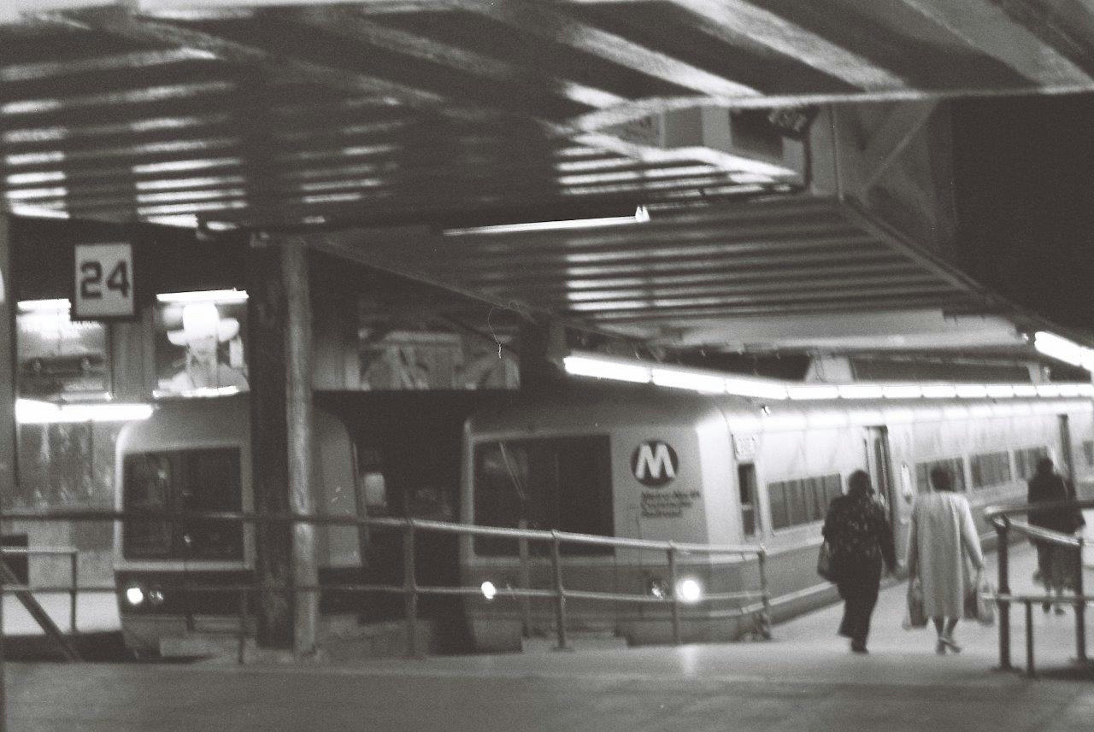 Imagen en blanco y negro de una estación de metro con un tren visible en la plataforma 24