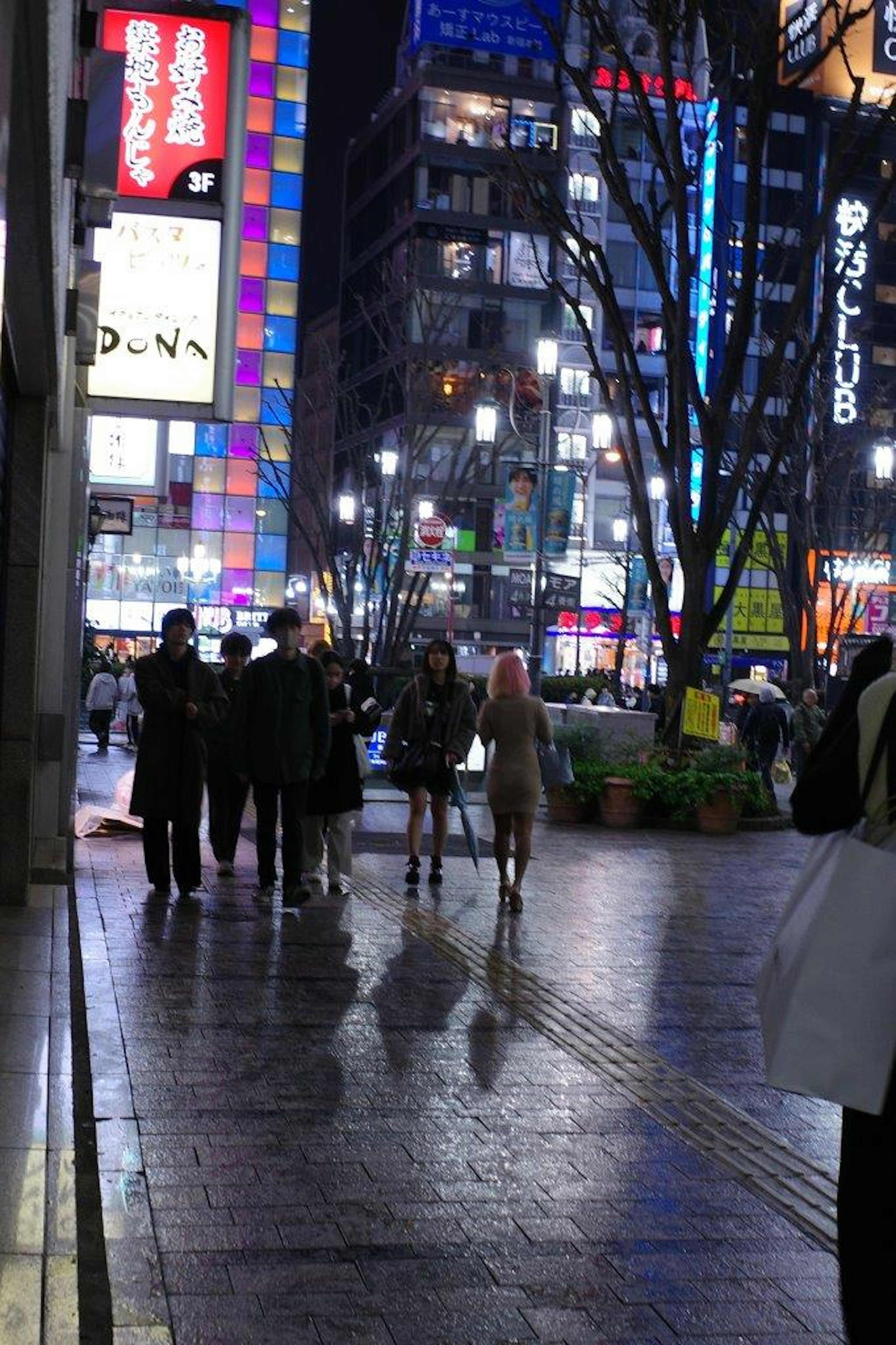 Persone che camminano in una vivace scena cittadina di notte insegne al neon brillanti illuminano l'area