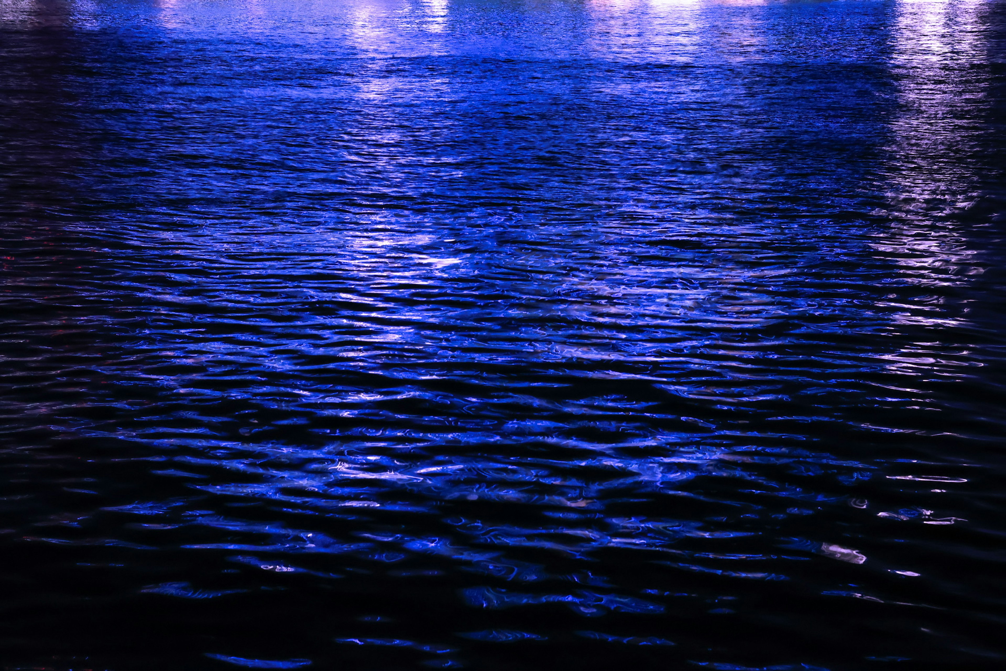 Beautiful night scene with reflections of light on a blue water surface