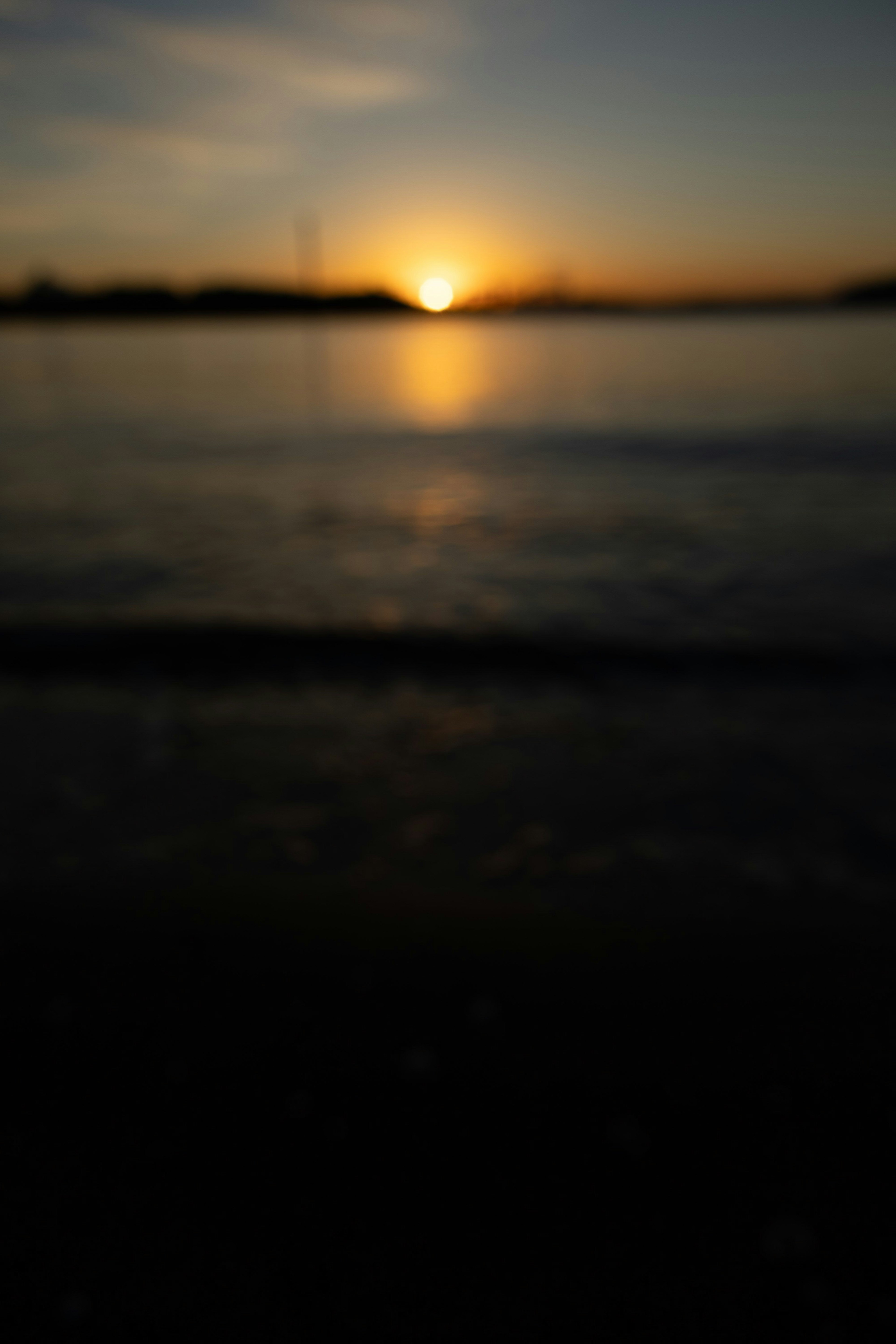 ぼやけた夕日が海に沈む様子