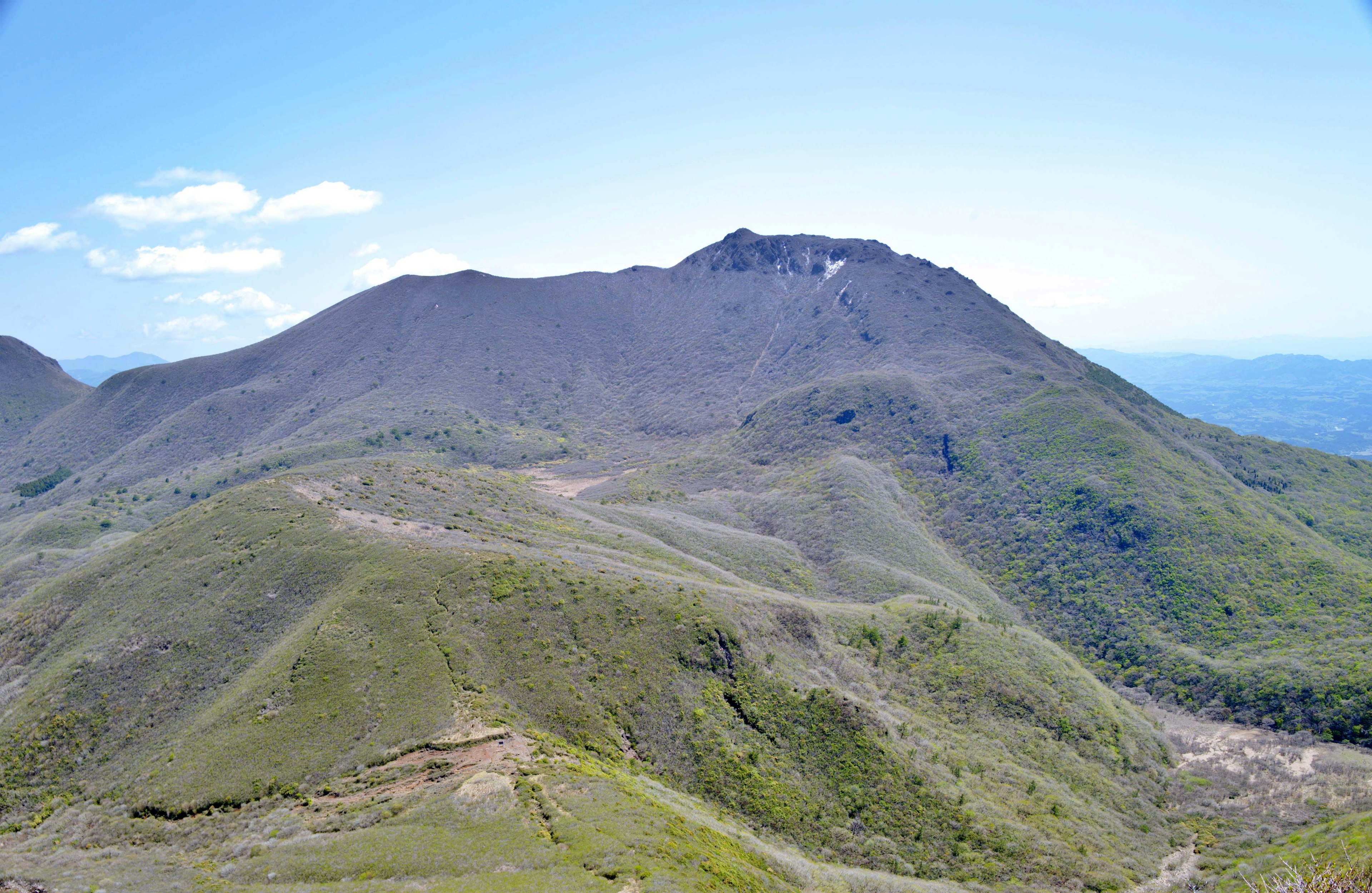 Gunung hijau subur di bawah langit biru cerah