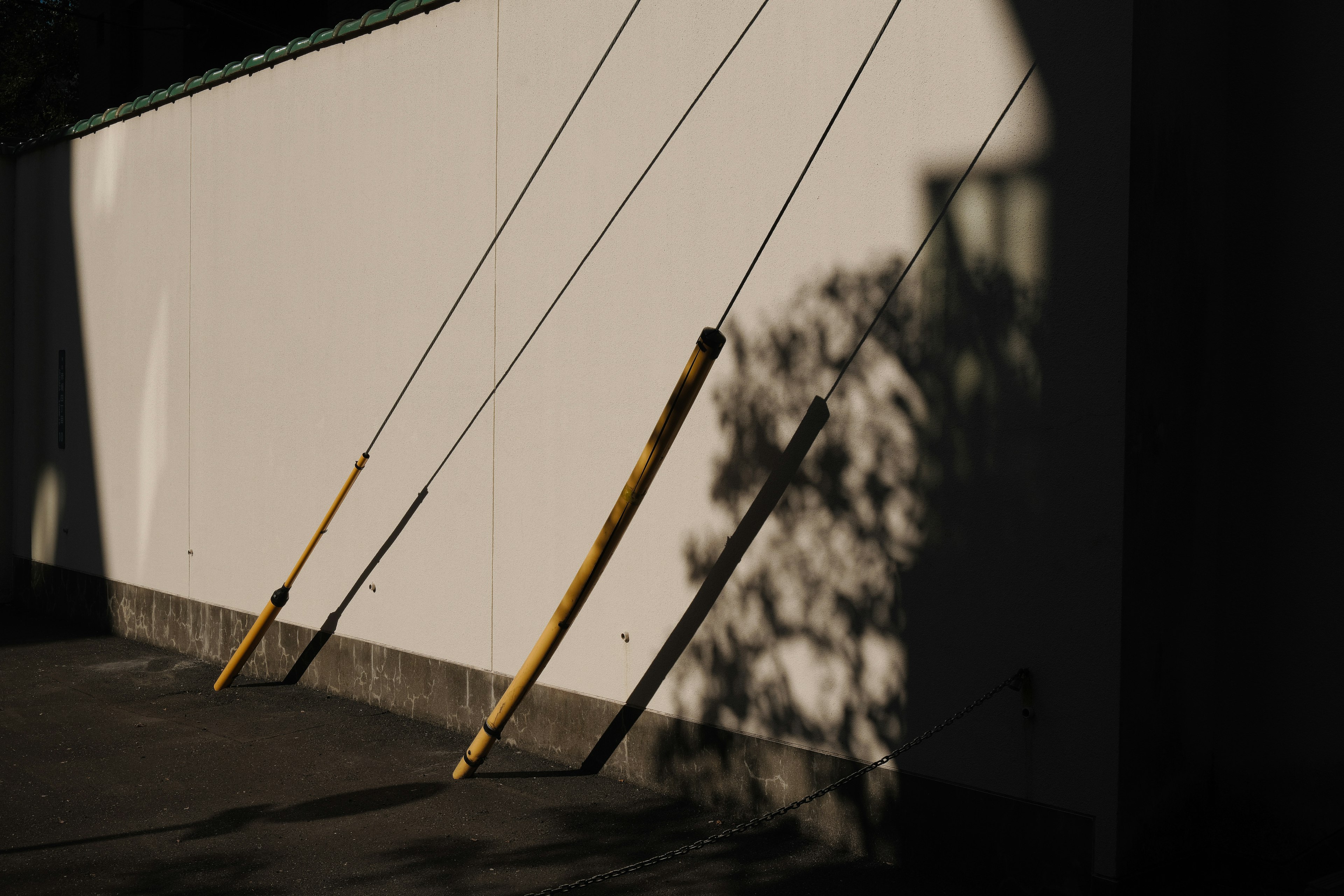 Three wooden poles casting shadows on a white wall