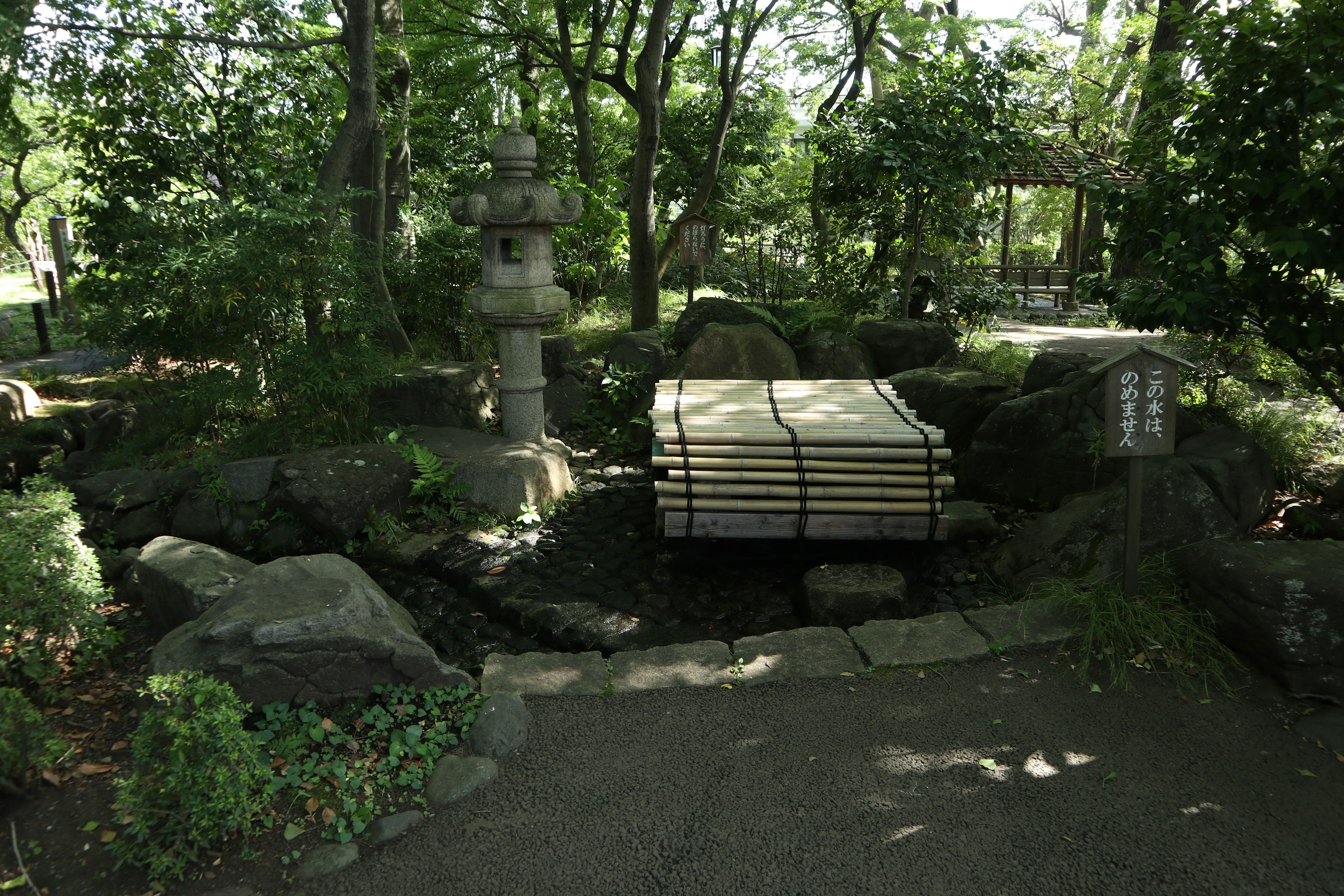 A serene Japanese garden scene featuring a stone lantern and lush greenery