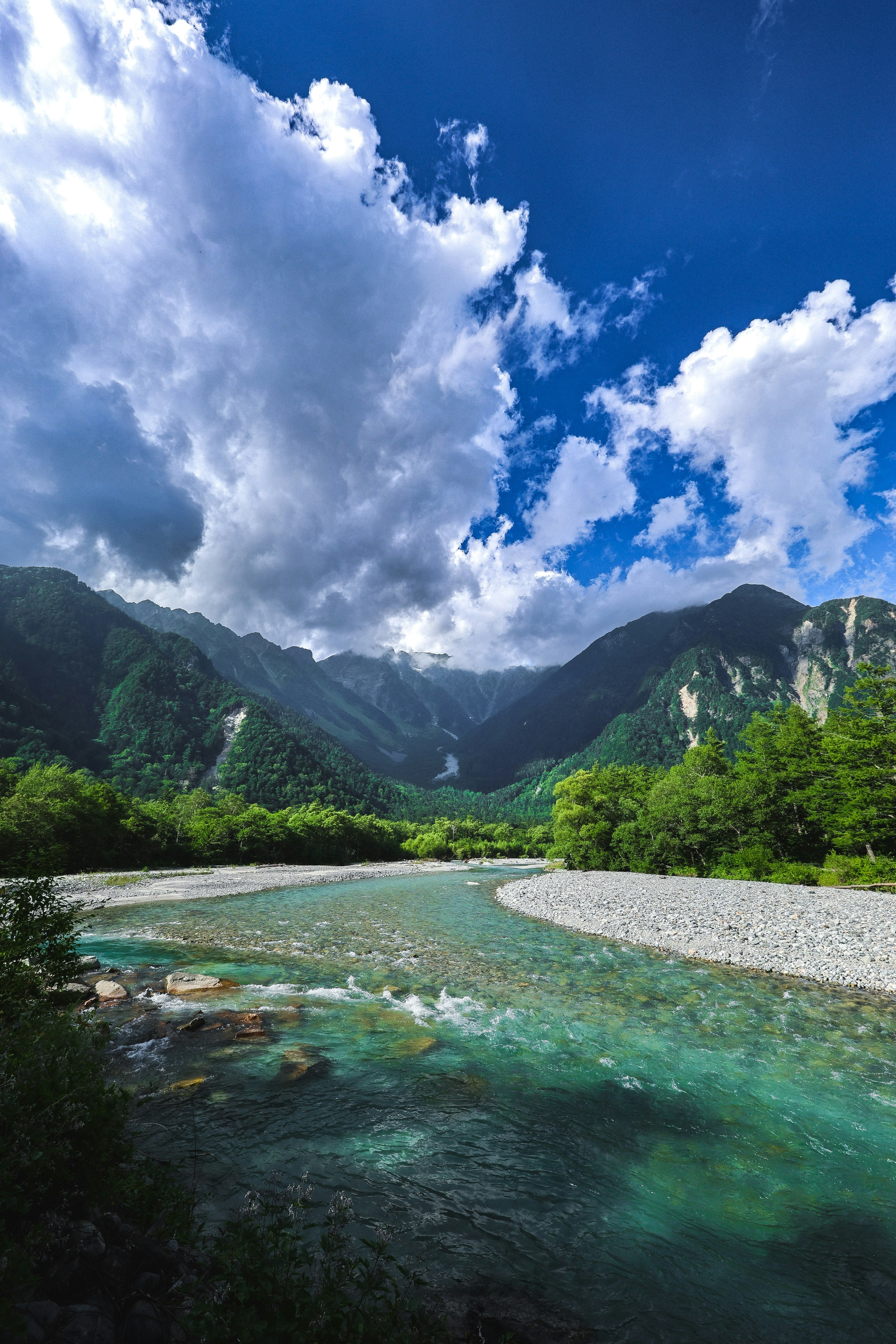 Rivière claire coulant sous de belles montagnes et un ciel bleu