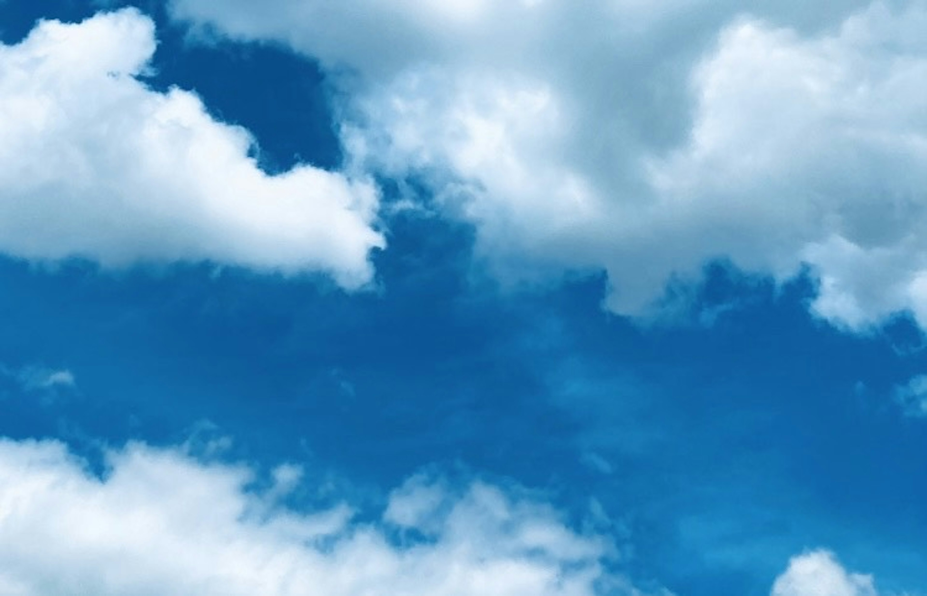 A clear blue sky with fluffy white clouds