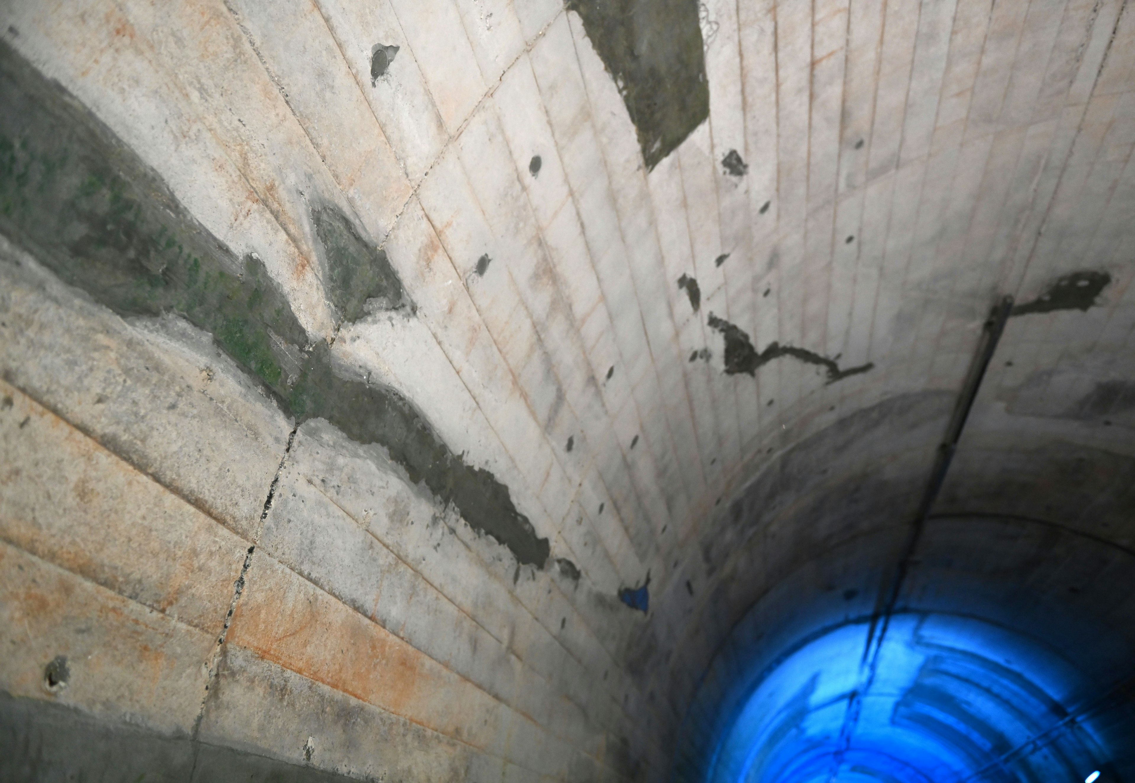 Imagen de una pared de túnel de concreto con luz azul brillando