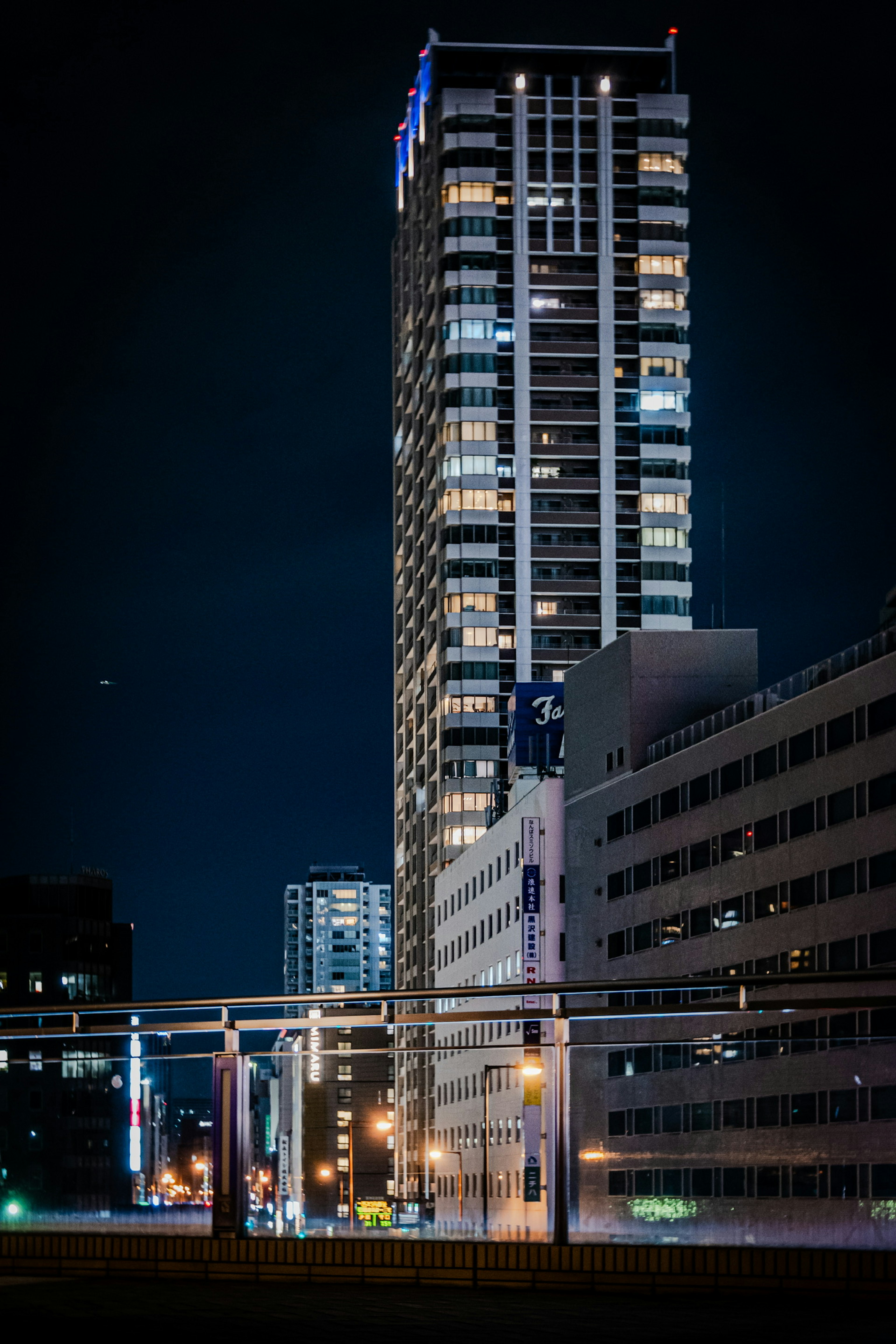 Nighttime cityscape featuring a tall skyscraper illuminated with lights