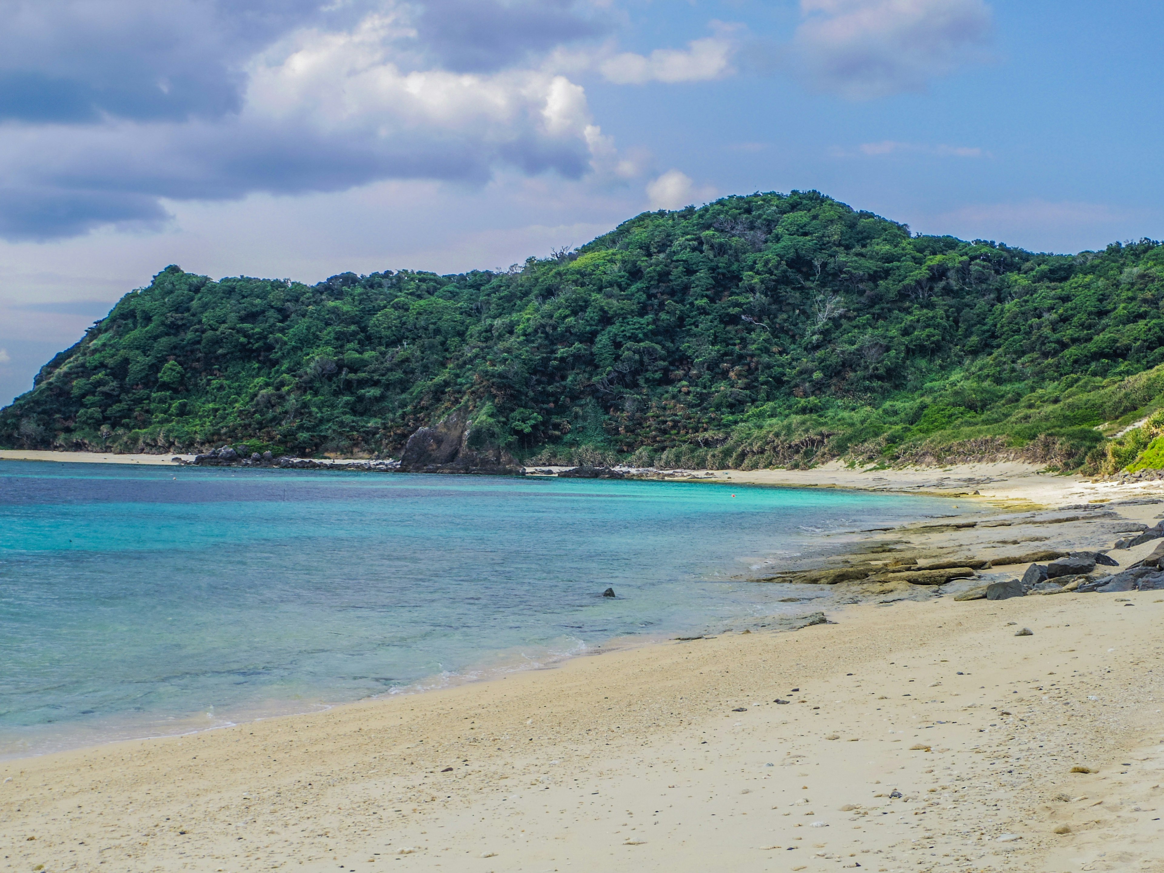 Pantai indah dengan air biru jernih bukit hijau di latar belakang