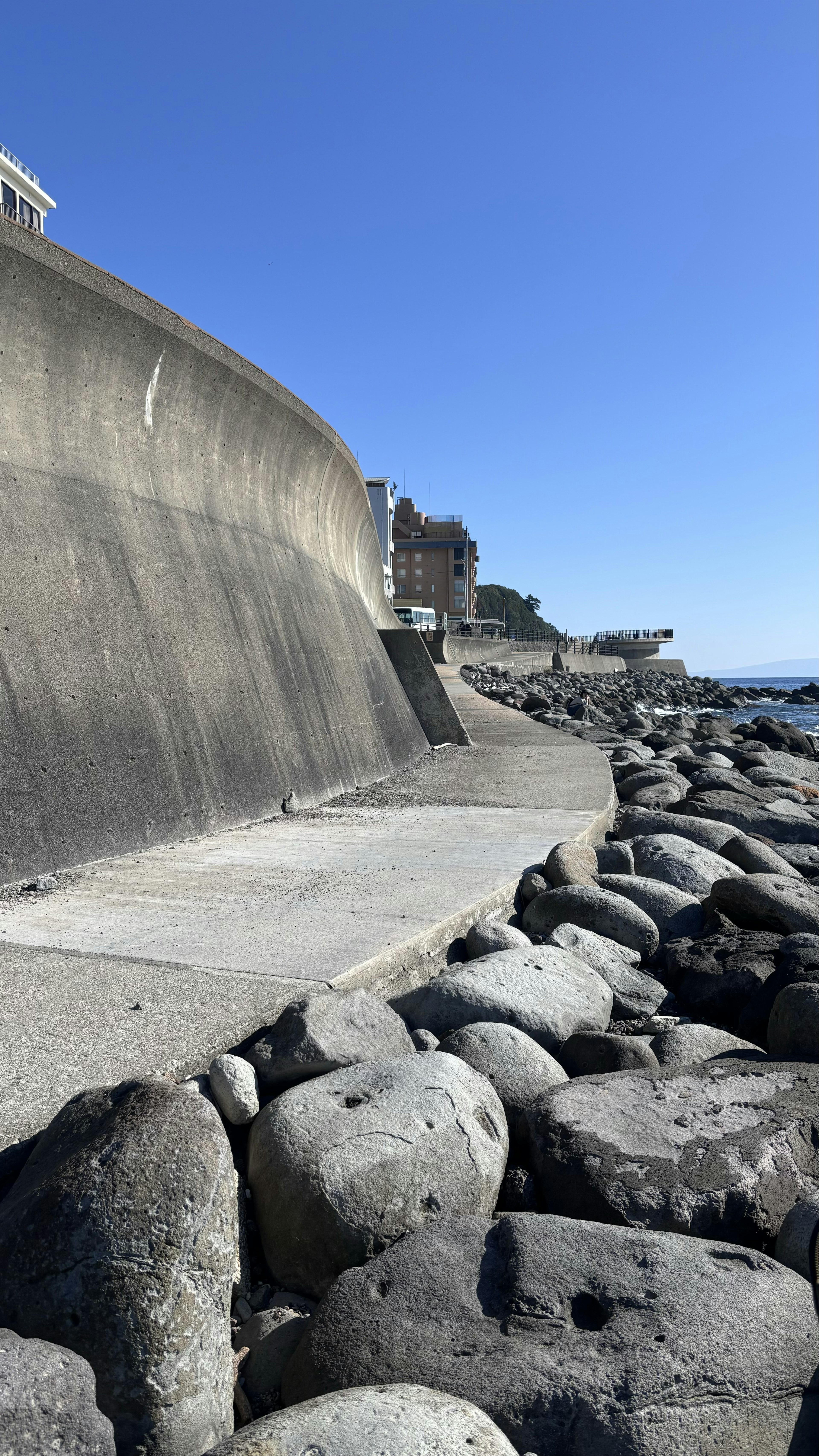 Muro di cemento lungo la costa con grandi rocce