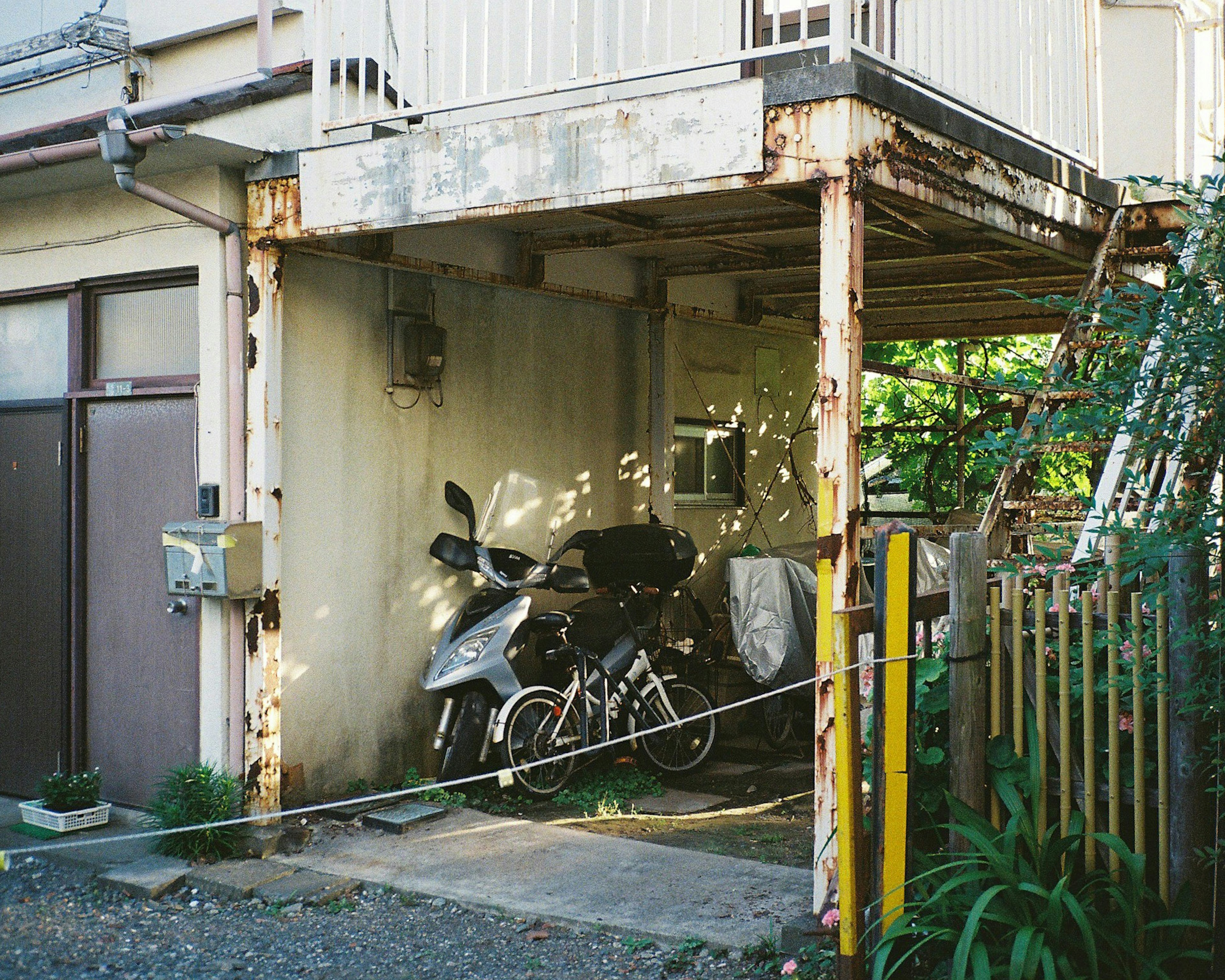 Immagine di una moto e una bicicletta parcheggiate sotto un vecchio edificio