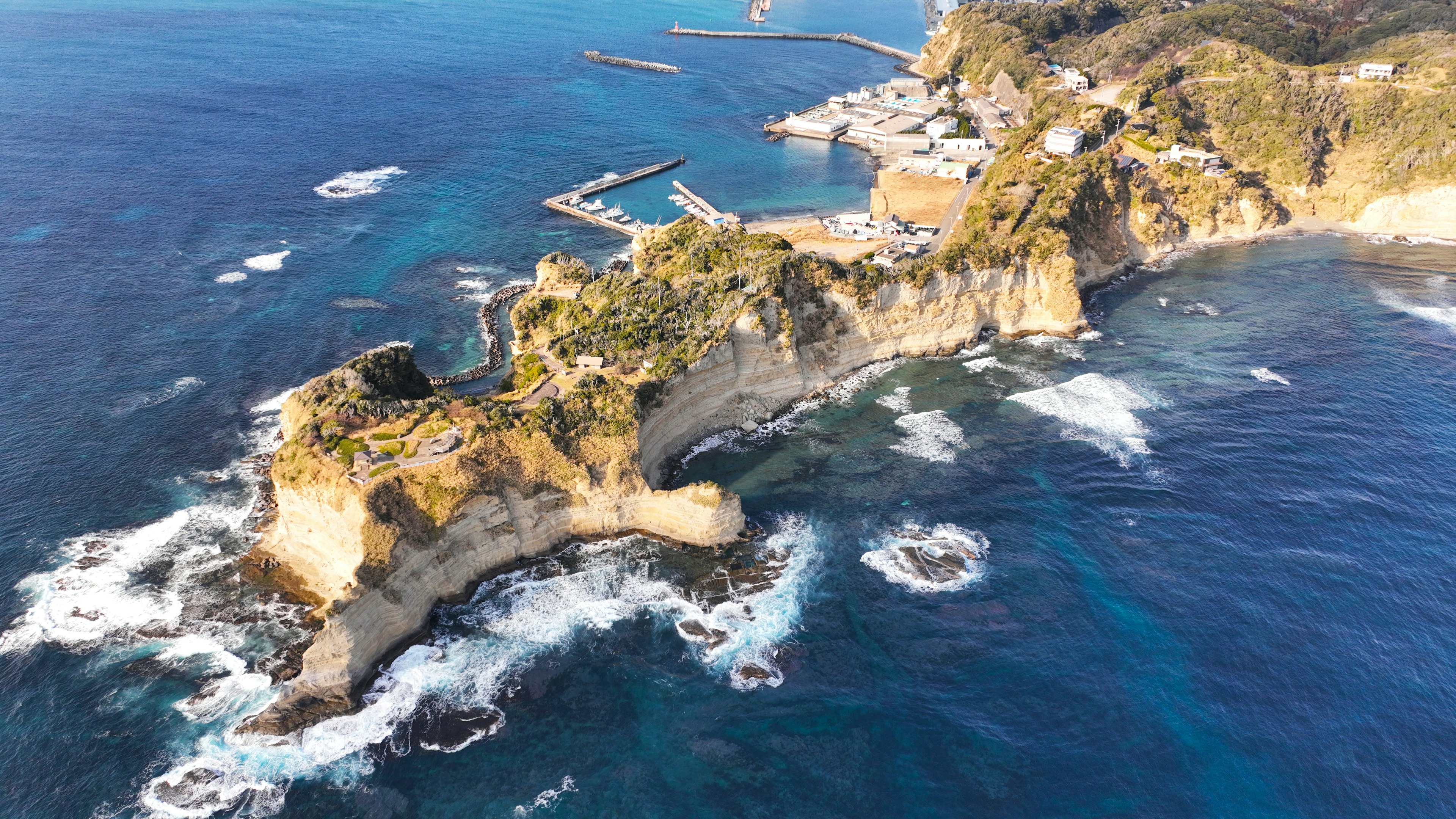 Vista mozzafiato di scogliere rocciose che si protendono nell'oceano con acque blu