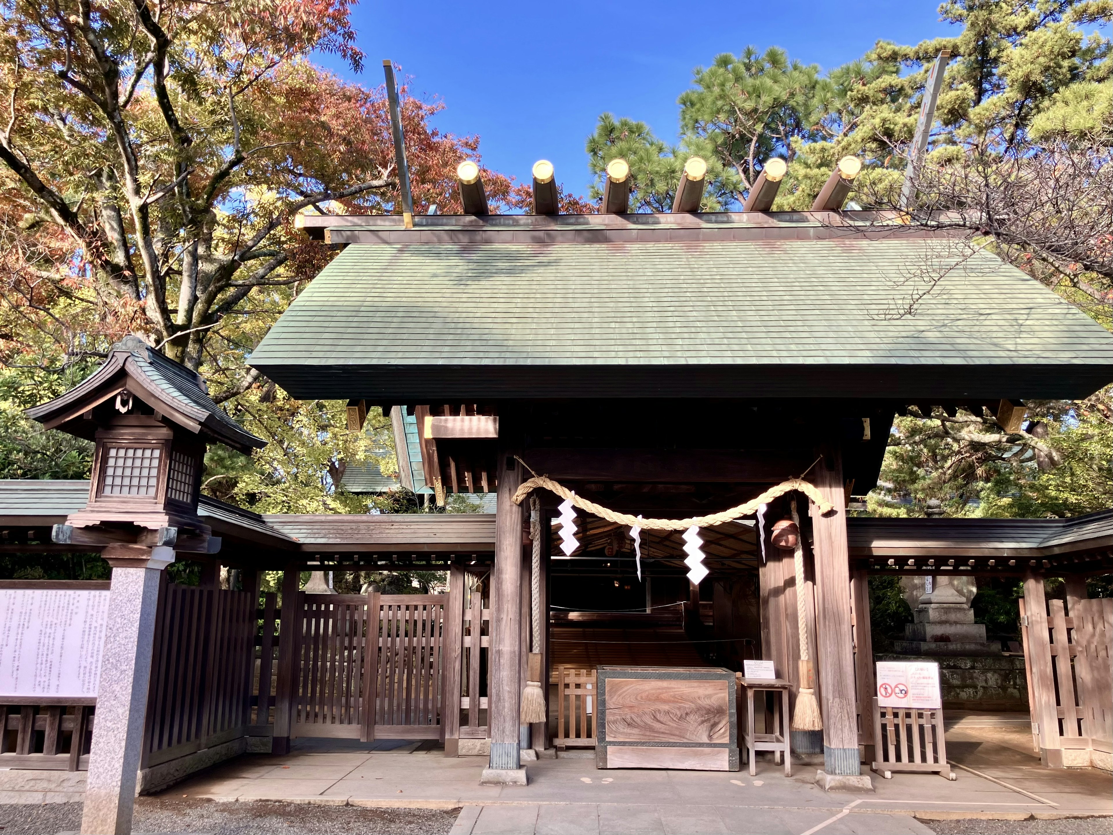 神社的入口，綠色屋頂，周圍被秋天的樹葉環繞