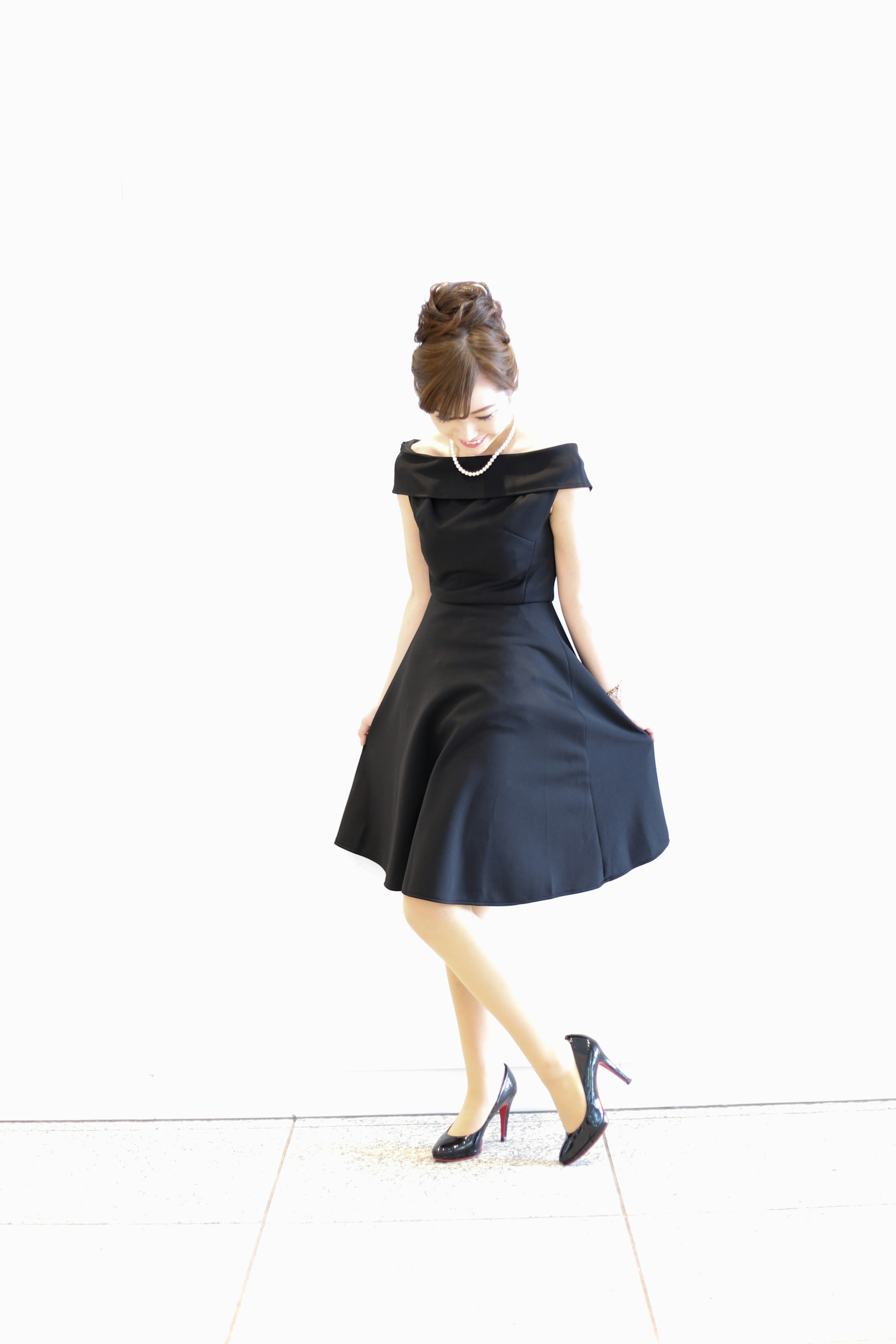 A woman in a black dress standing against a white background