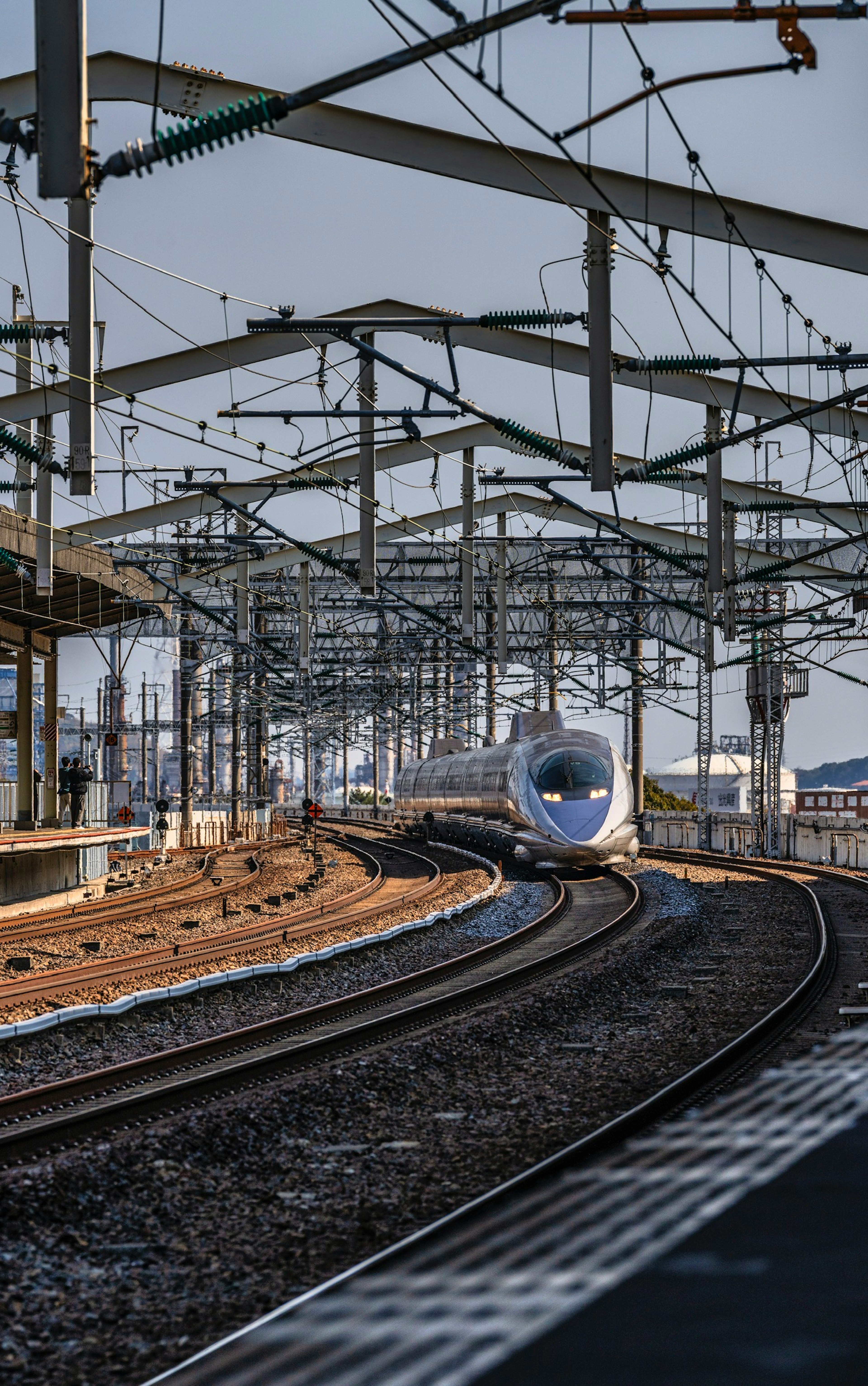 Shinkansen-Zug, der auf kurvigen Gleisen fährt, mit sichtbaren Oberleitungsstrukturen