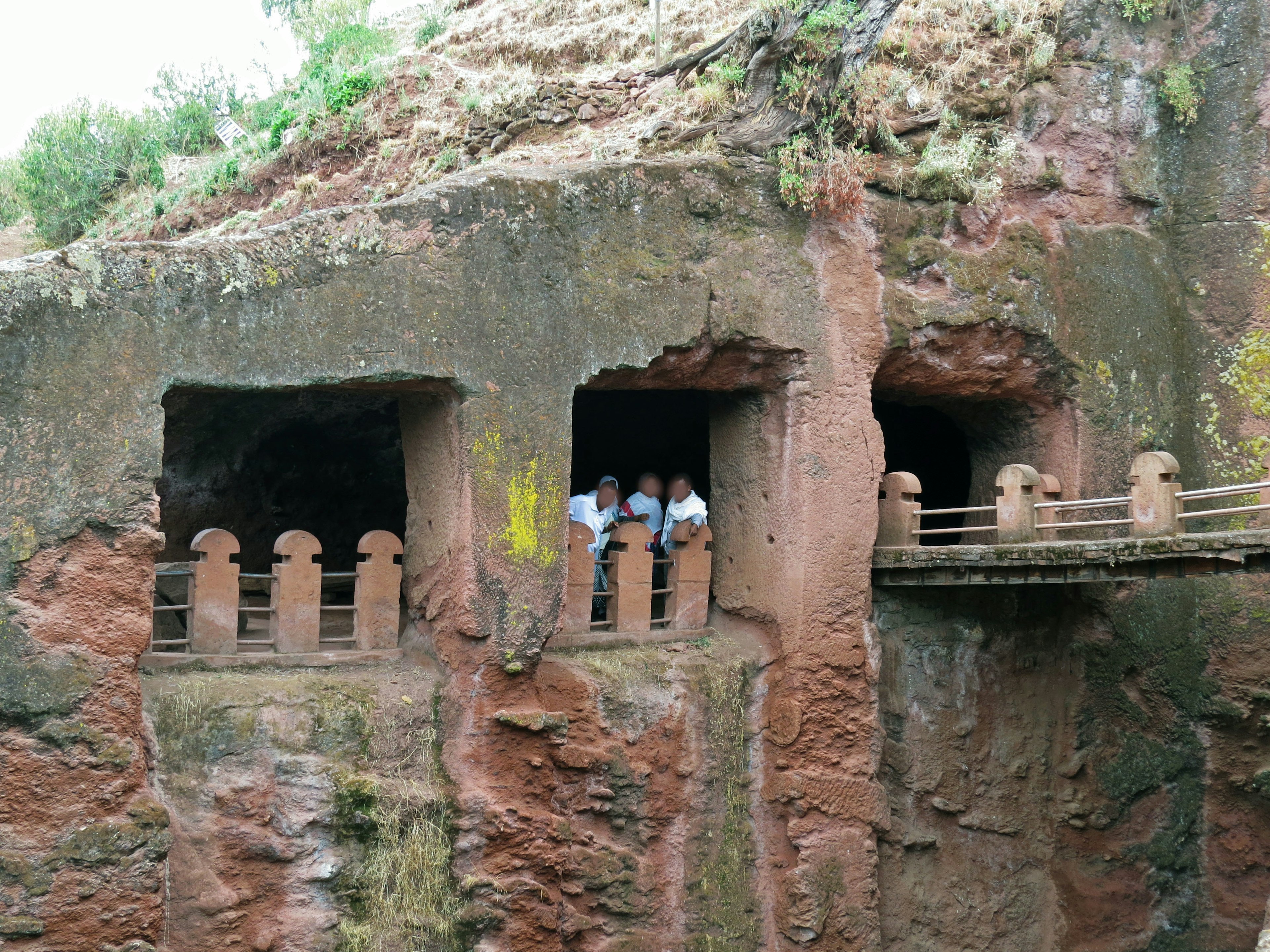 Structures anciennes sculptées dans la roche avec des personnes visibles