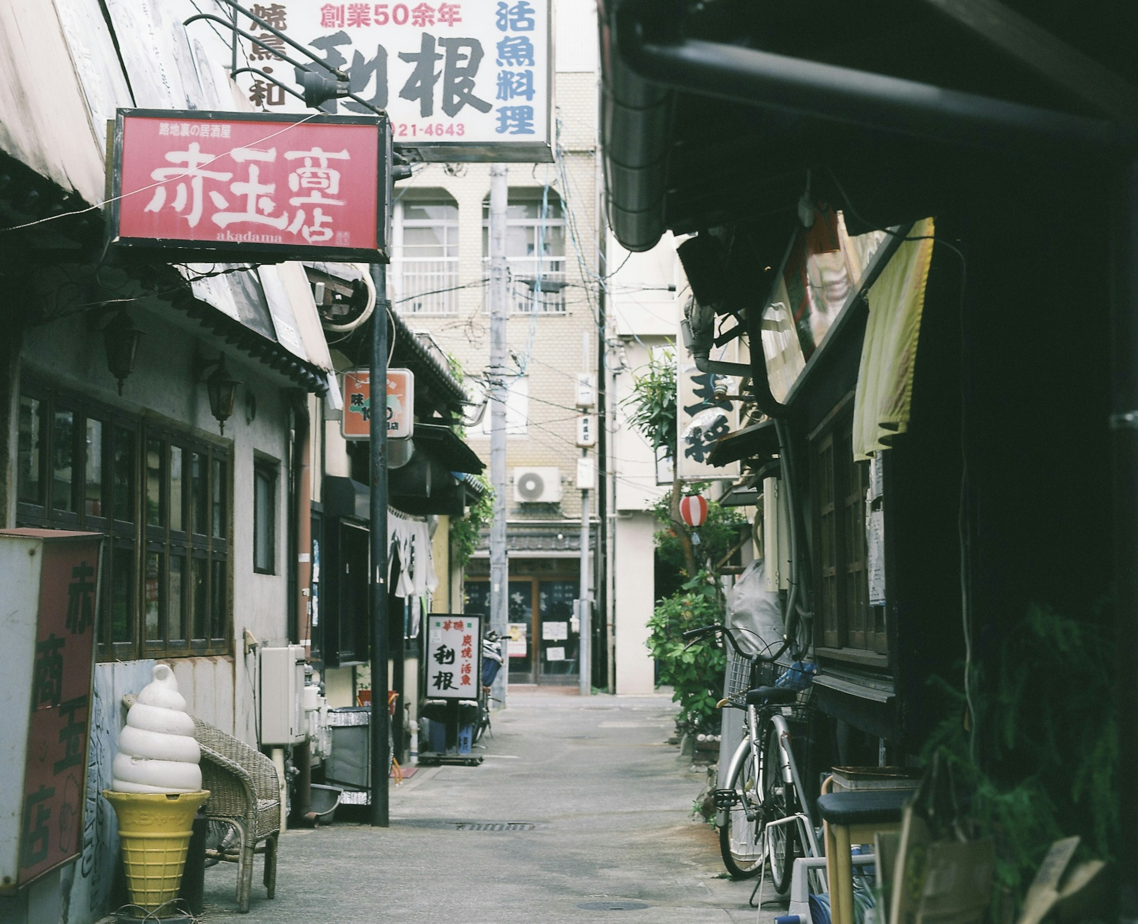 狭い路地にある古い店舗と看板が並ぶ風景