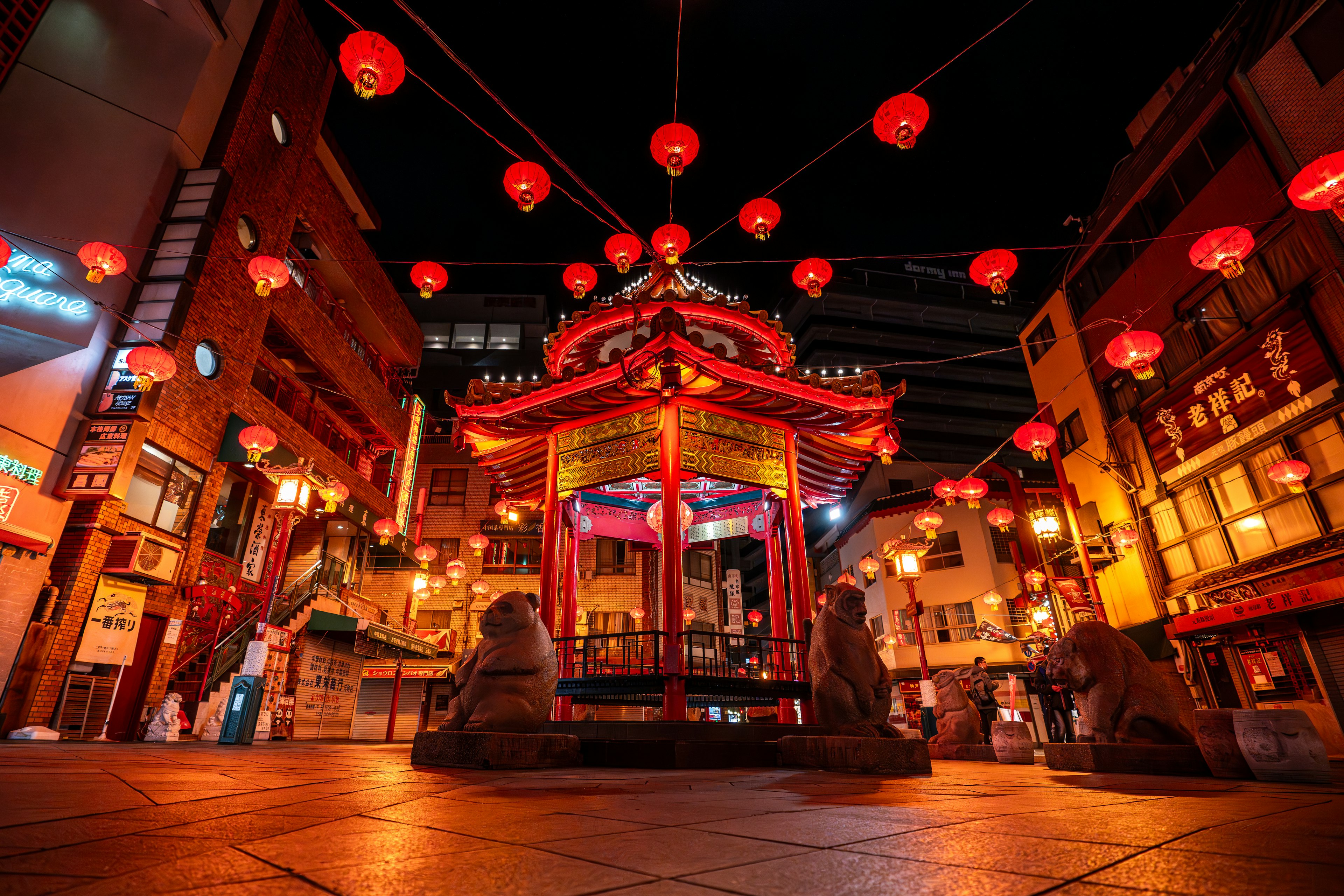 装饰有红灯笼的中国风亭子在热闹的夜街上