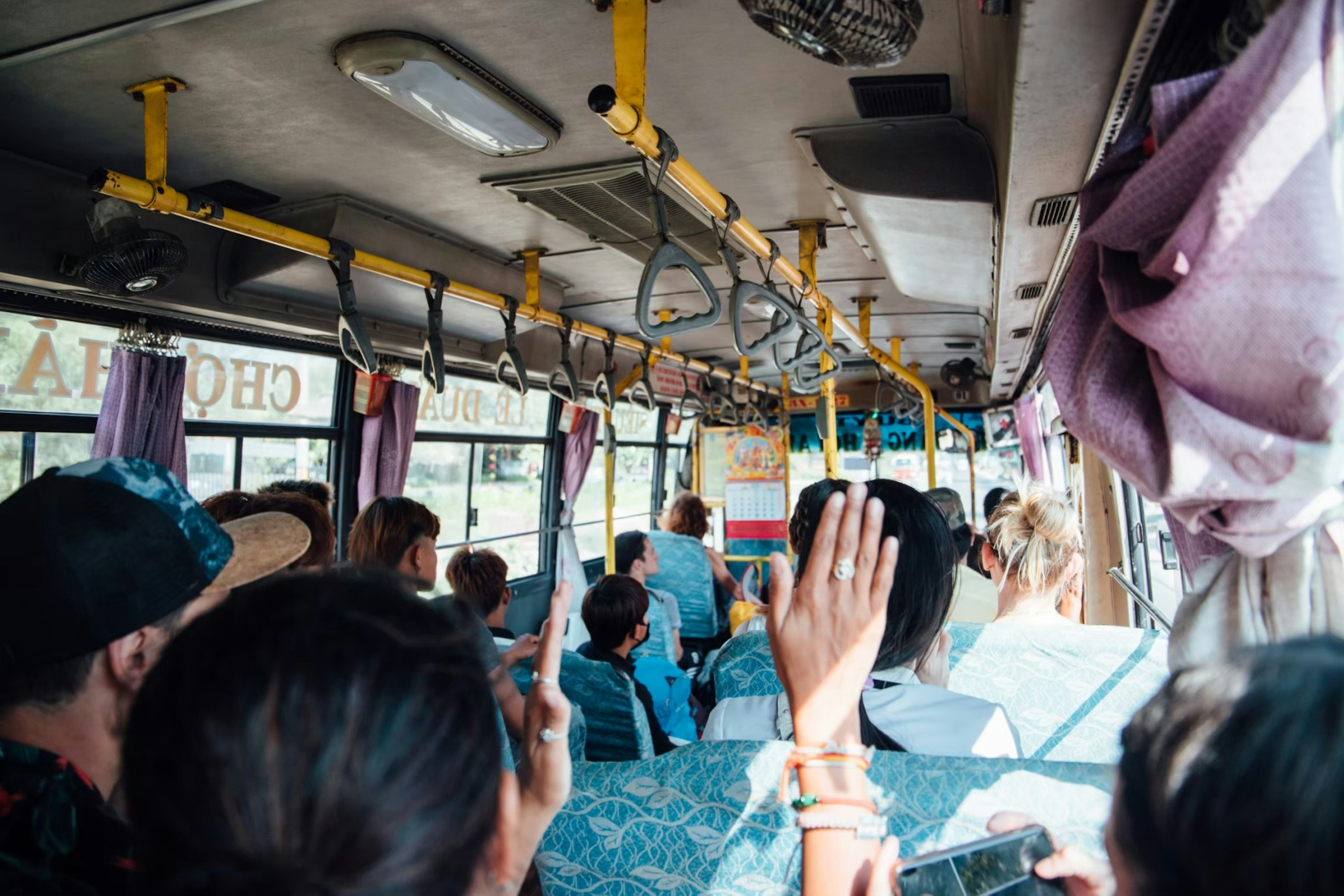 Interno di un autobus con passeggeri che alzano le mani