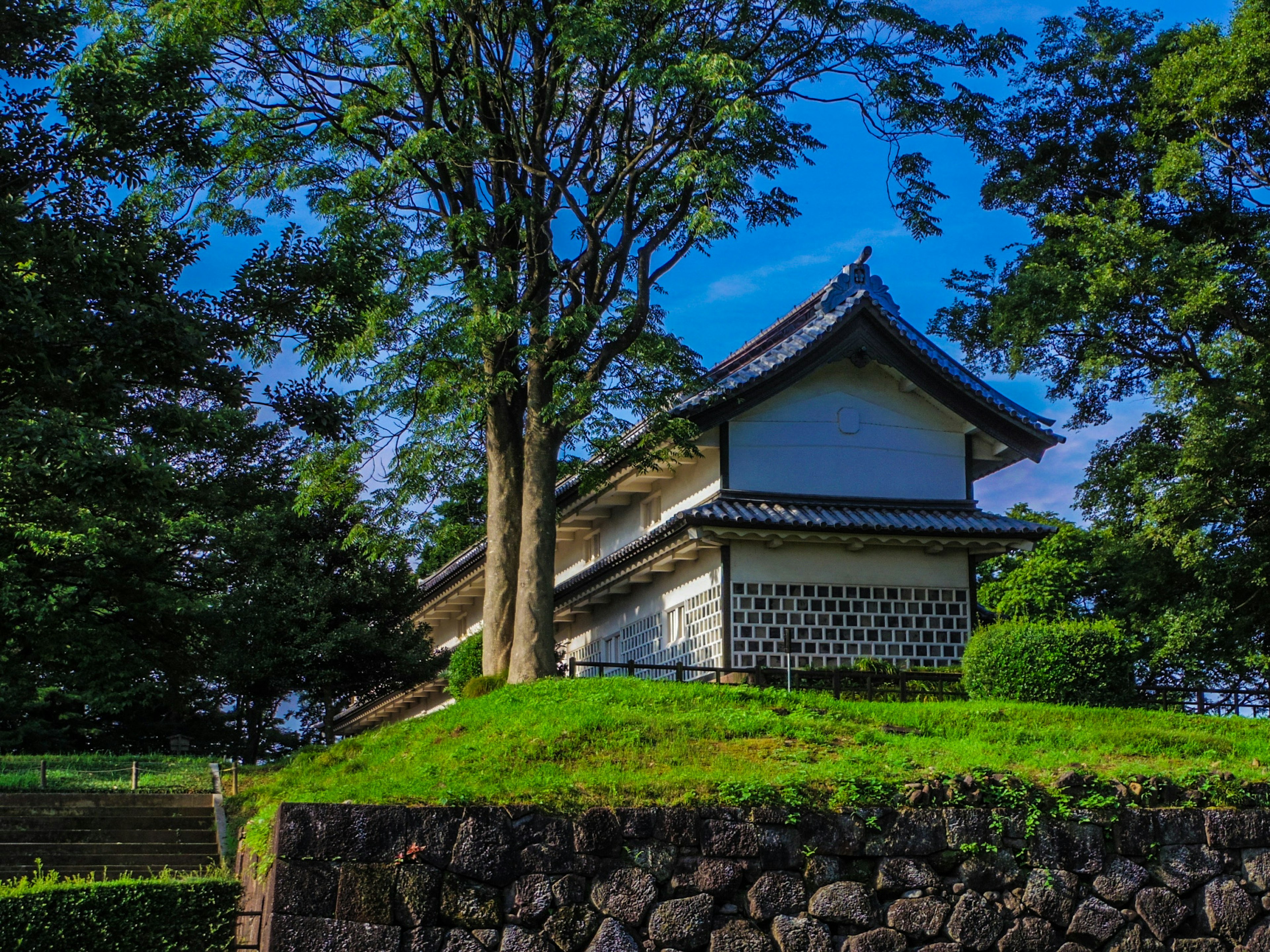 Traditionelles japanisches Gebäude umgeben von Grün unter einem klaren blauen Himmel