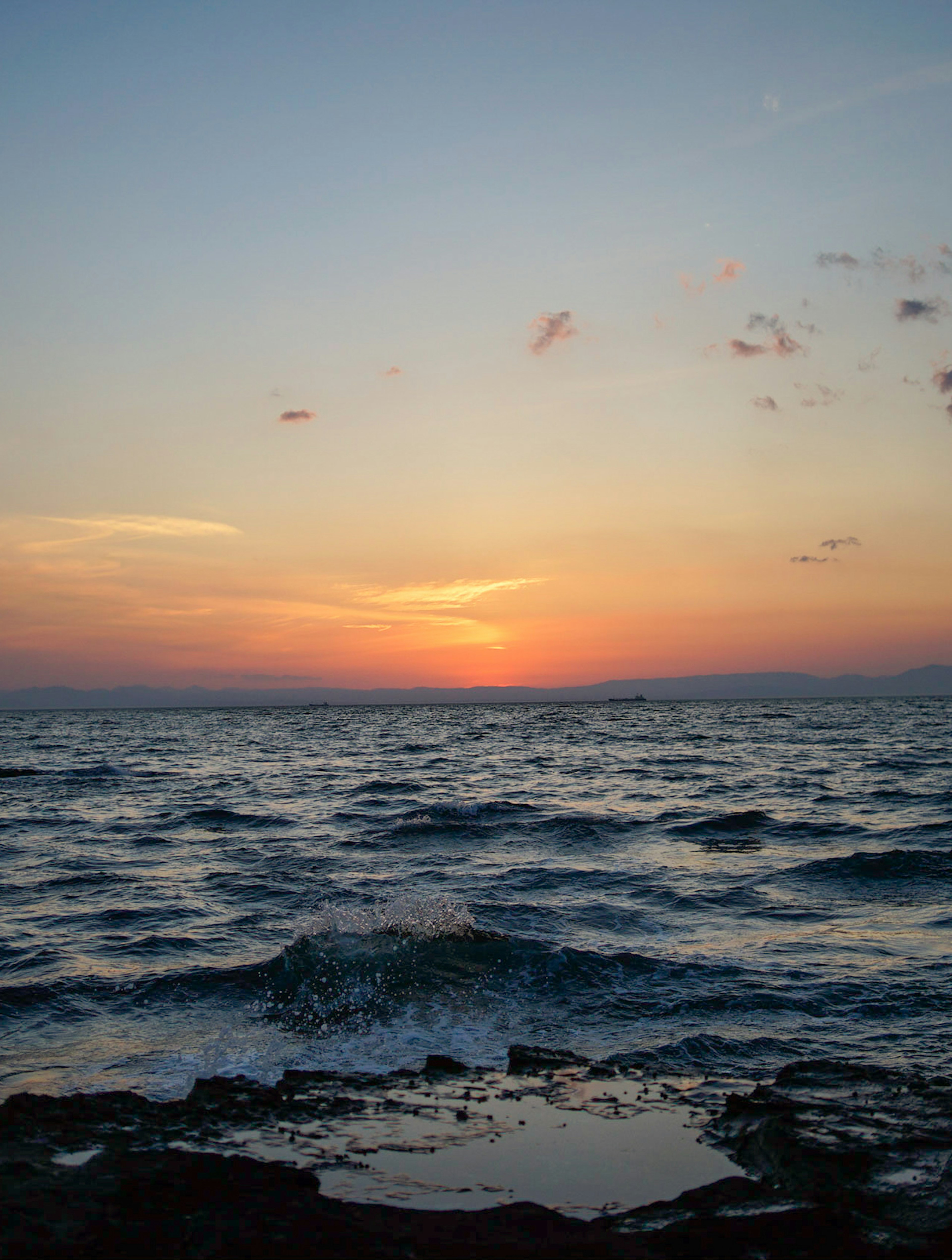 夕日が海に沈む美しい風景波が岩に打ち寄せる