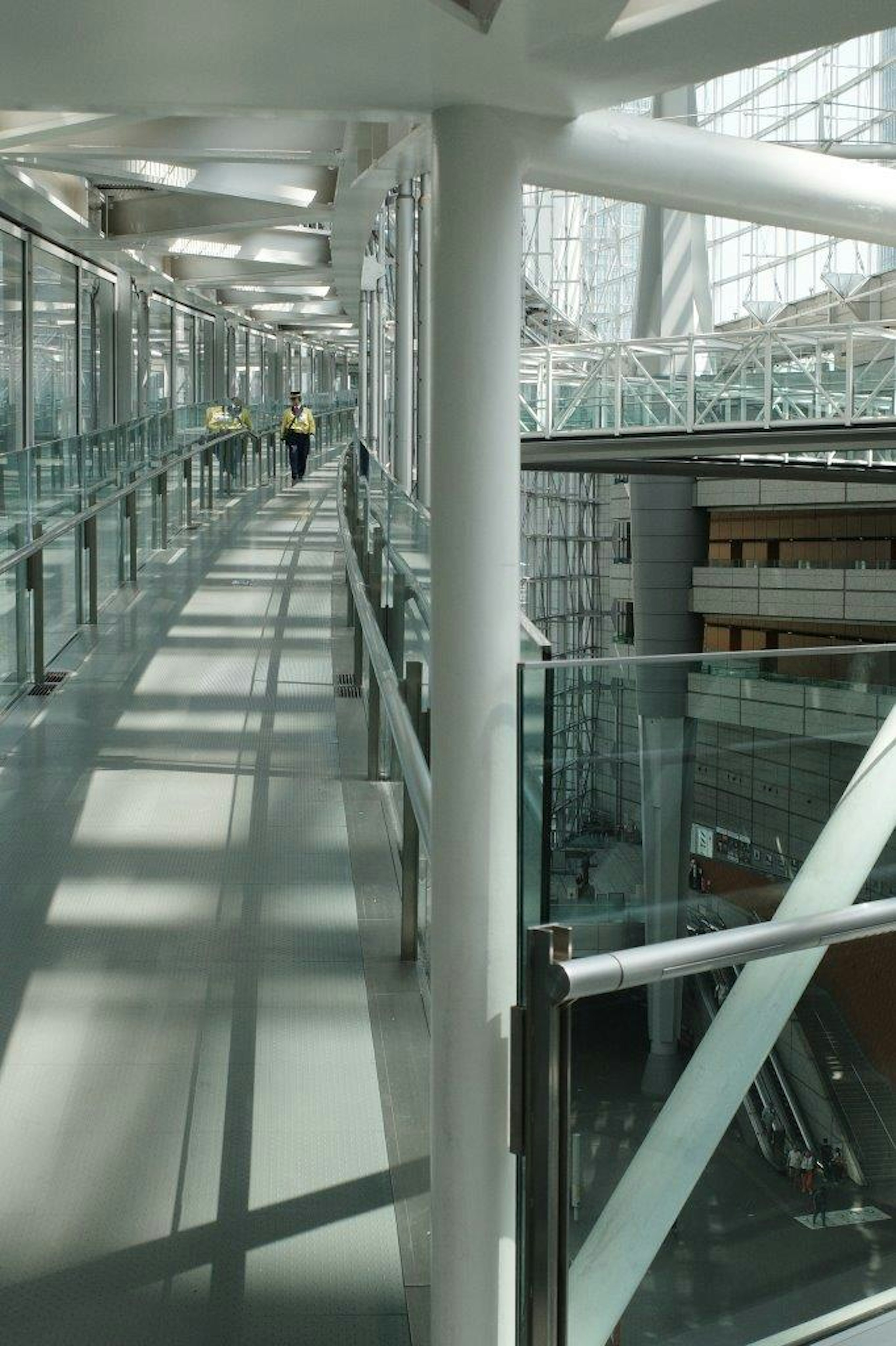 A modern building interior with a bright glass walkway and a person standing