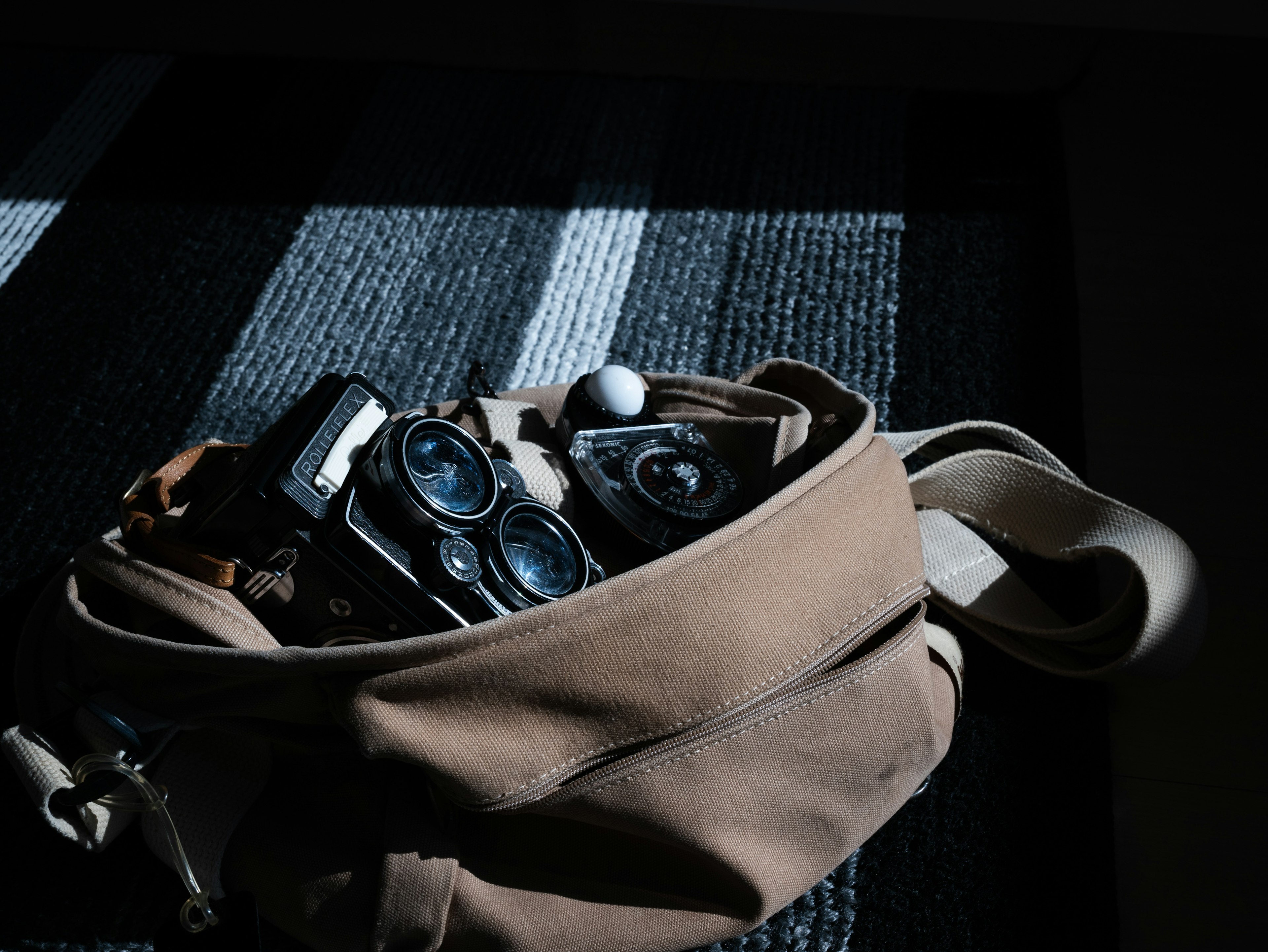 Un sac marron rempli de caméras et d'objets divers reposant sur une surface rayée