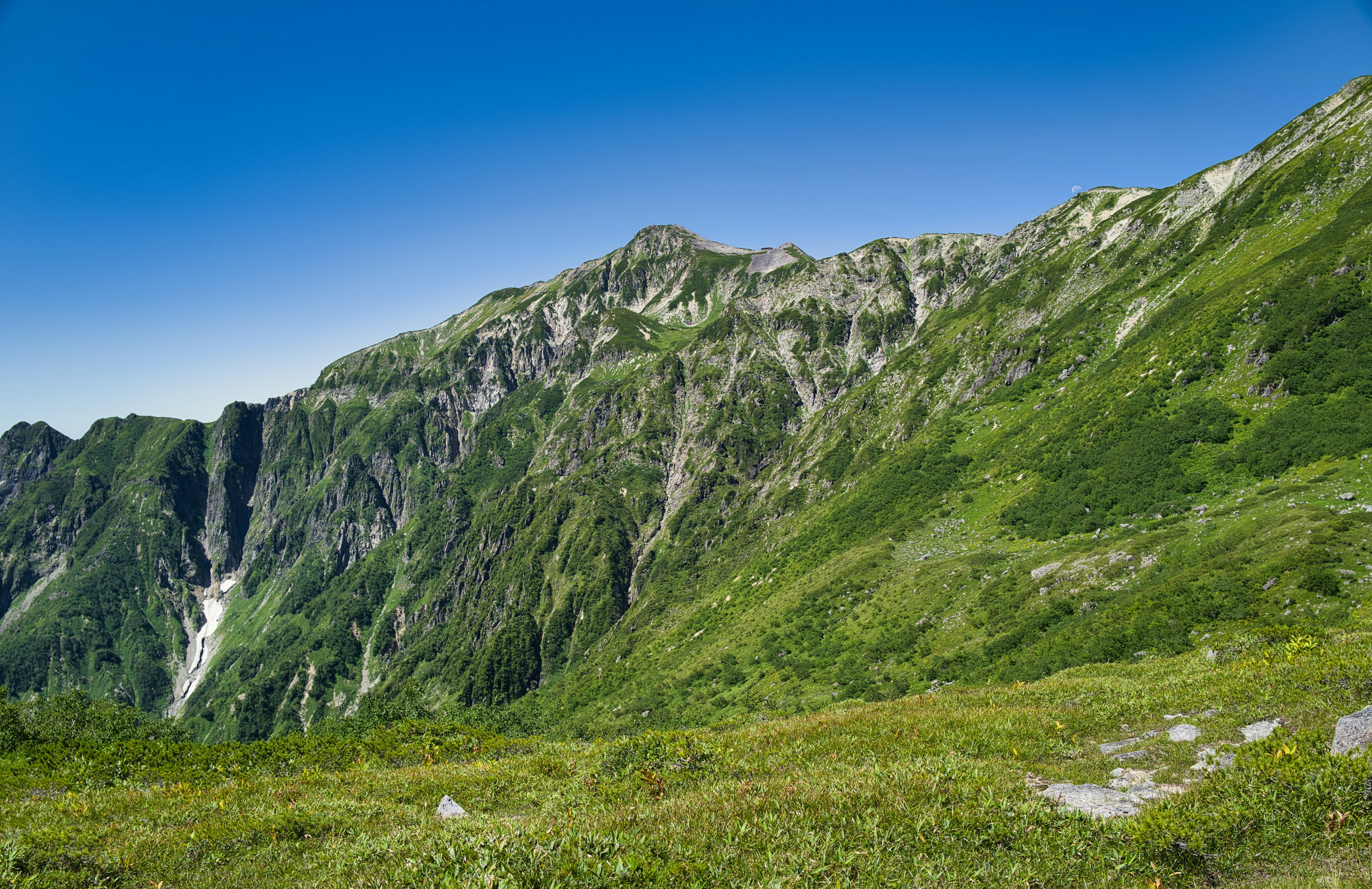 Paisaje montañoso verde bajo un cielo azul claro