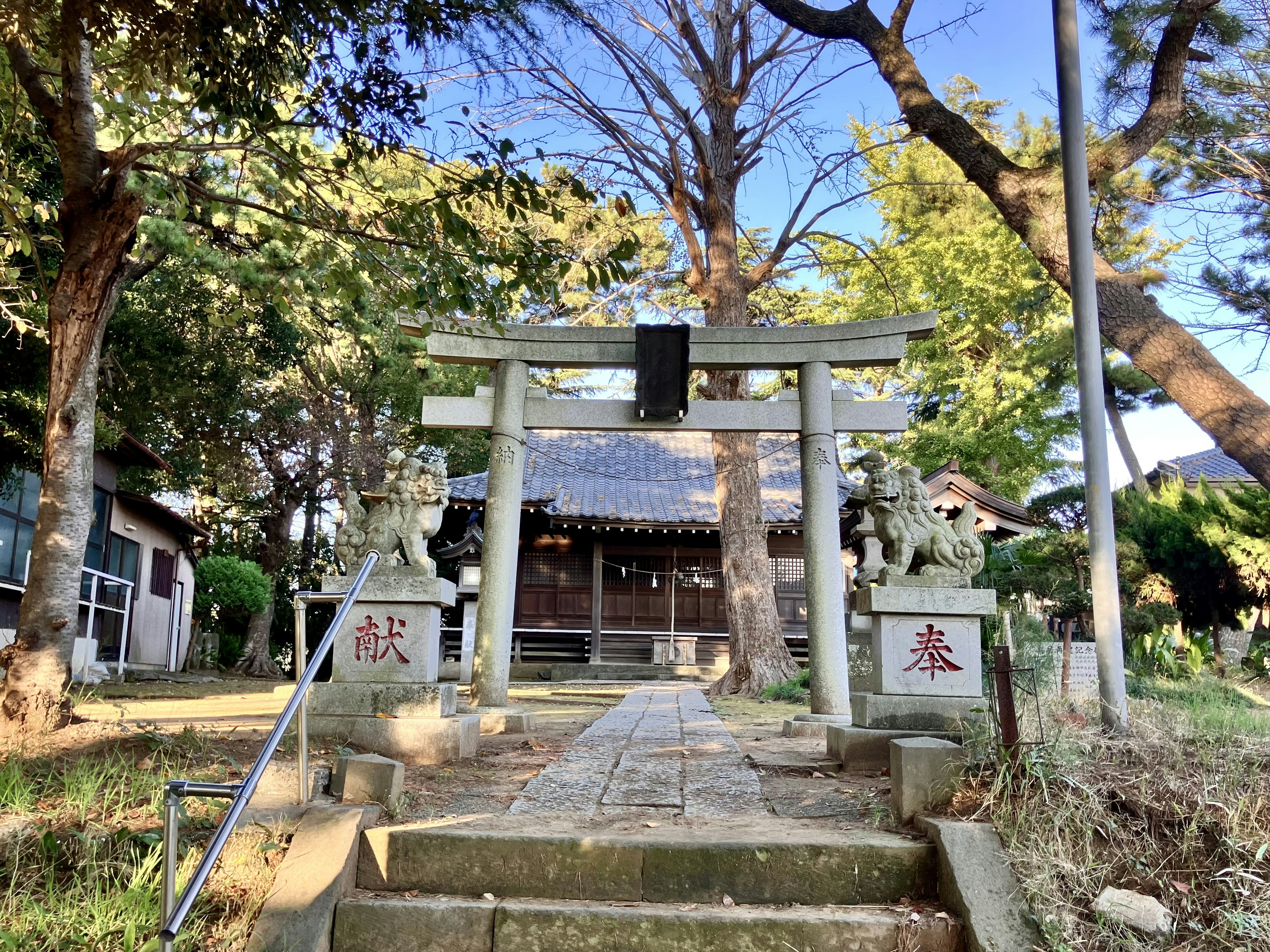 Pemandangan tenang dari pintu masuk kuil dengan gerbang torii dan singa penjaga