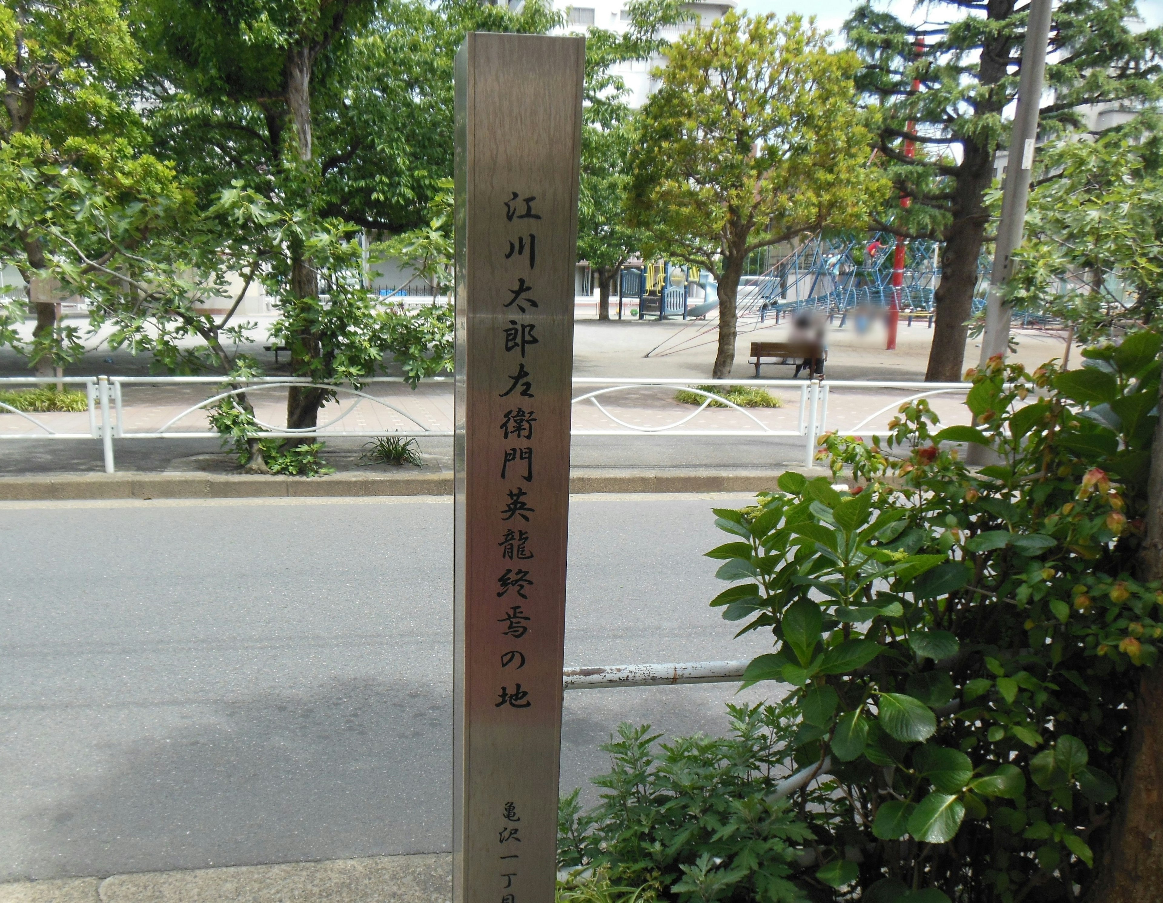 Information sign at a park entrance surrounded by greenery