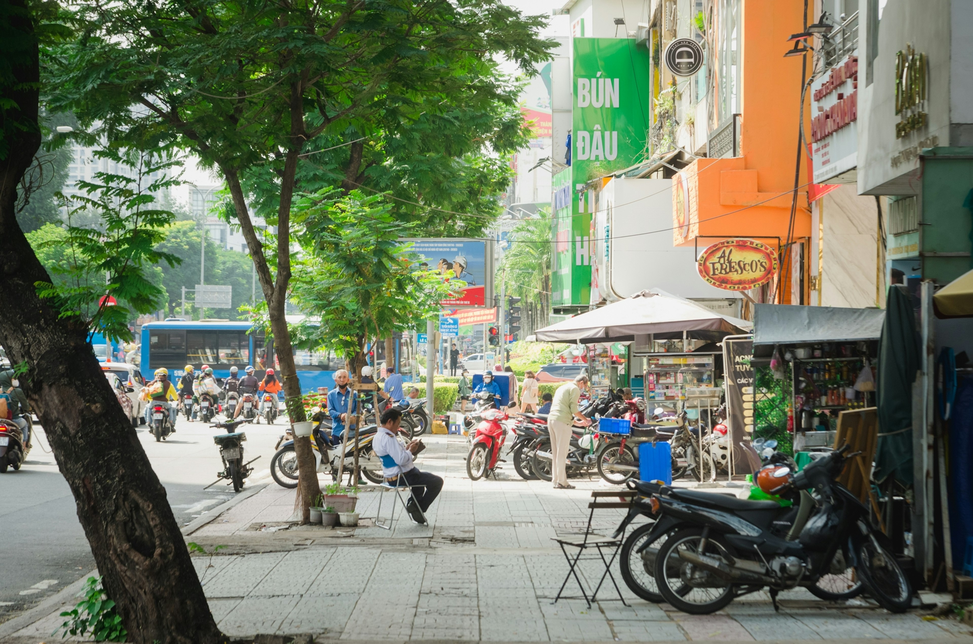 街の風景にバイクとテーブルが並ぶカフェがある