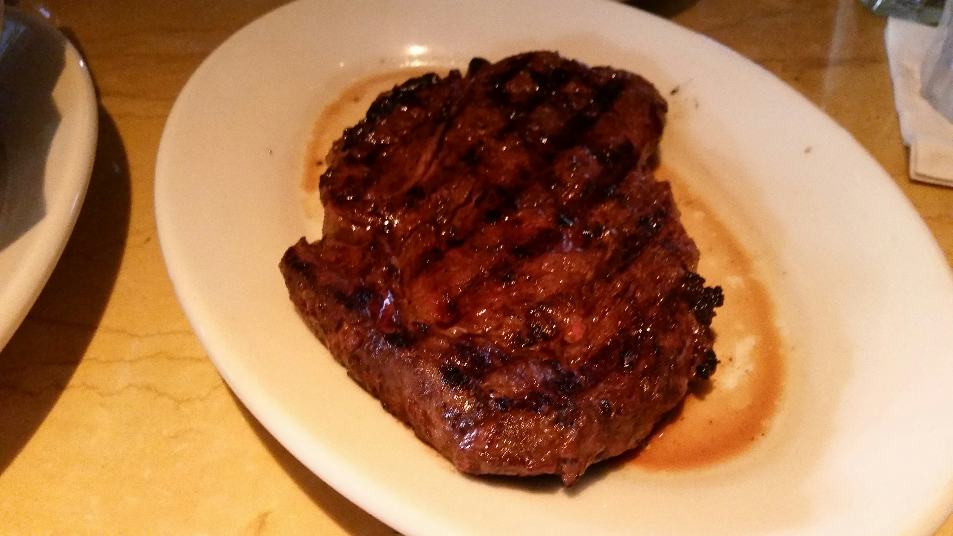 Bistec jugoso a la parrilla con marcas de parrilla en un plato blanco