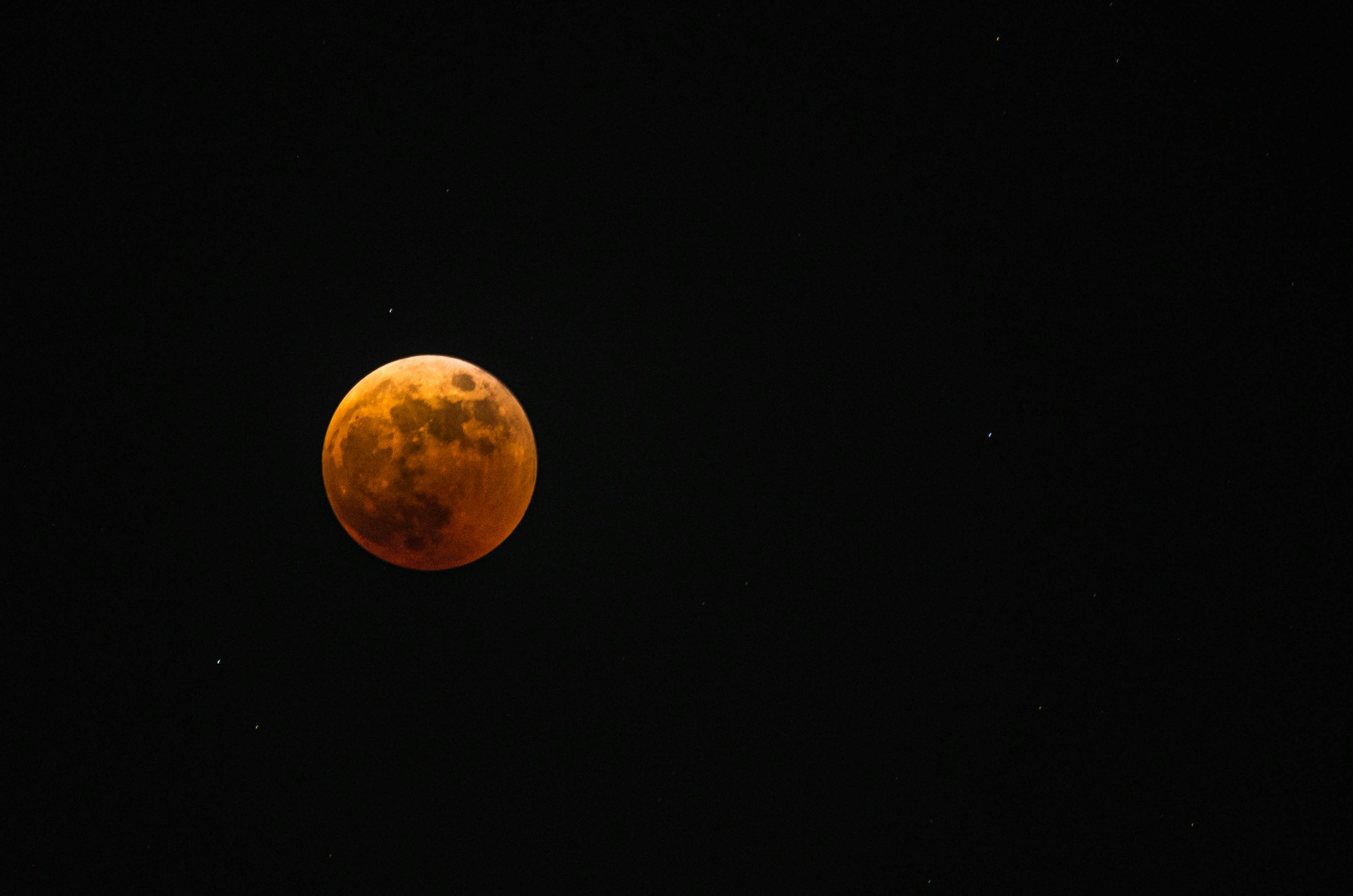 Luna naranja con fondo oscuro y estrellas