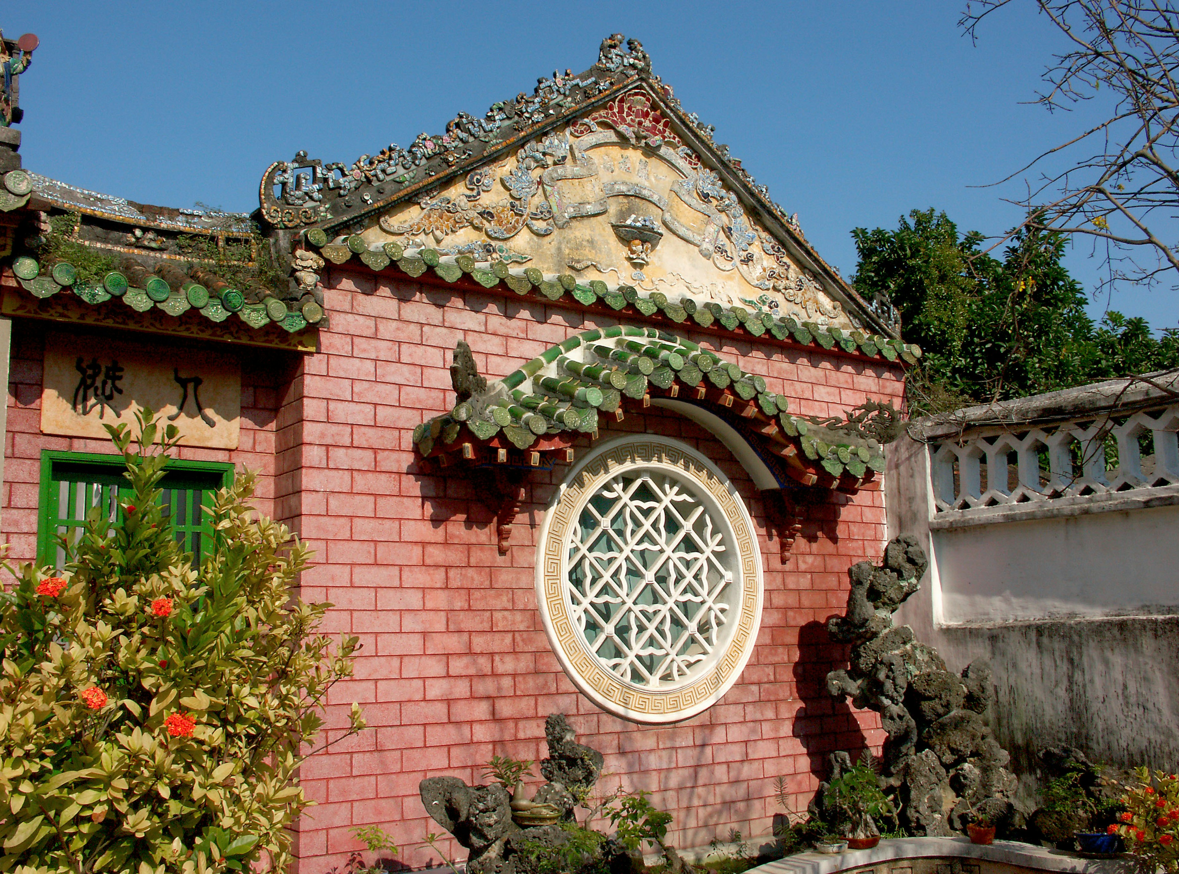 Edificio tradicional chino con ventana decorativa y plantas coloridas