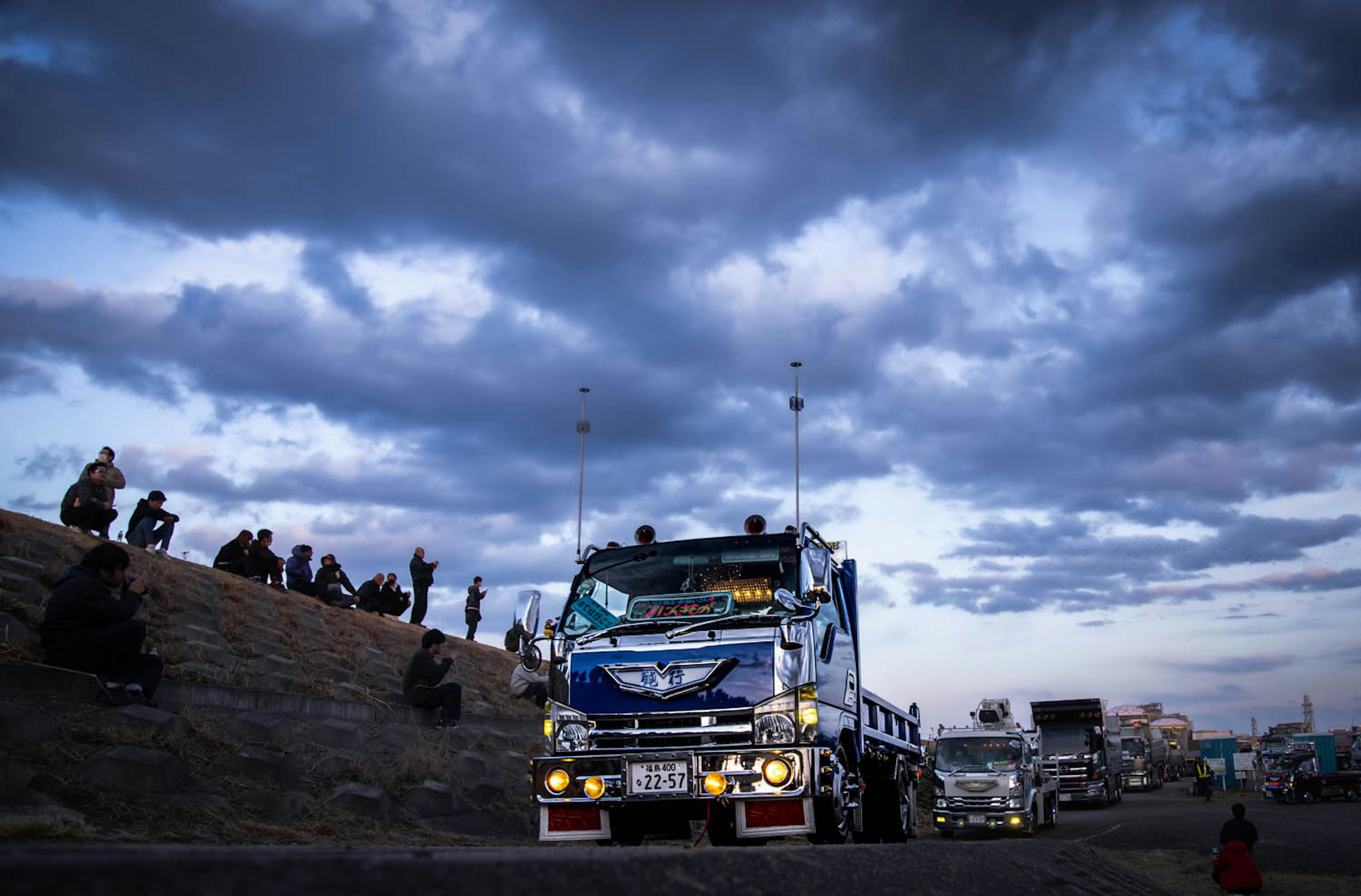 Un camion circulant sous un ciel nuageux avec des personnes assises autour