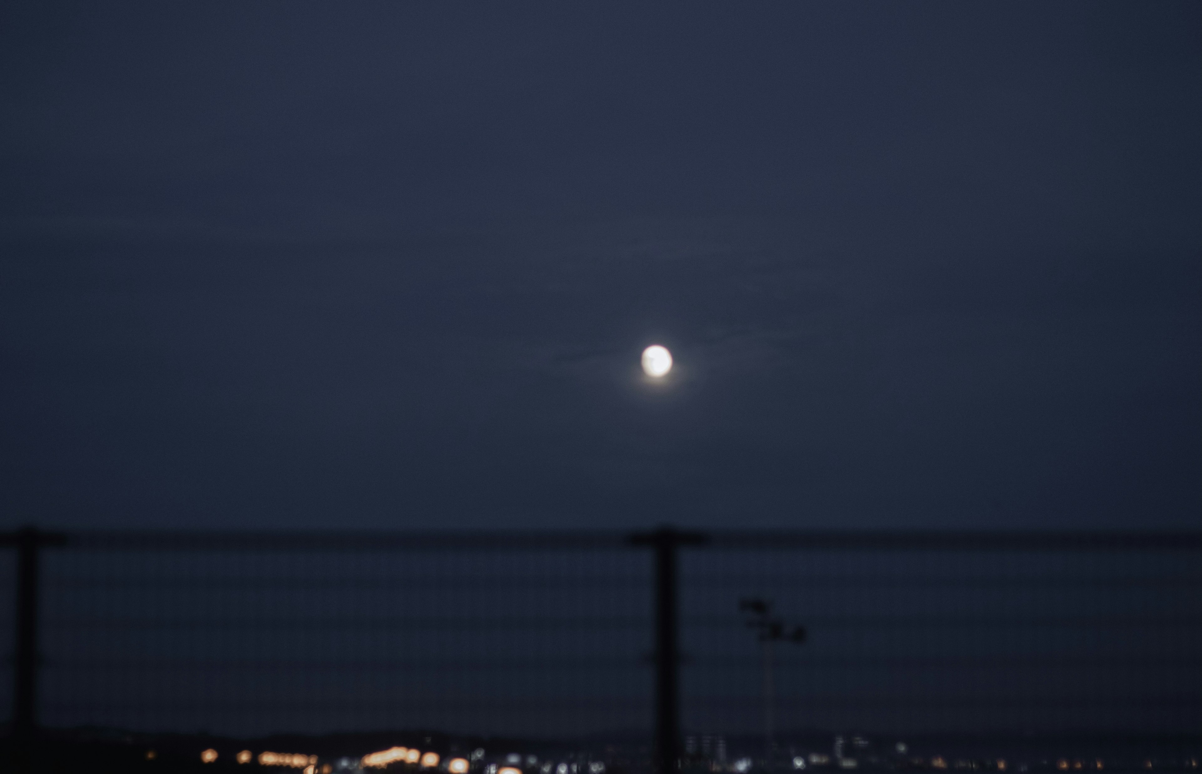 Bright moon in a dark sky surrounded by clouds