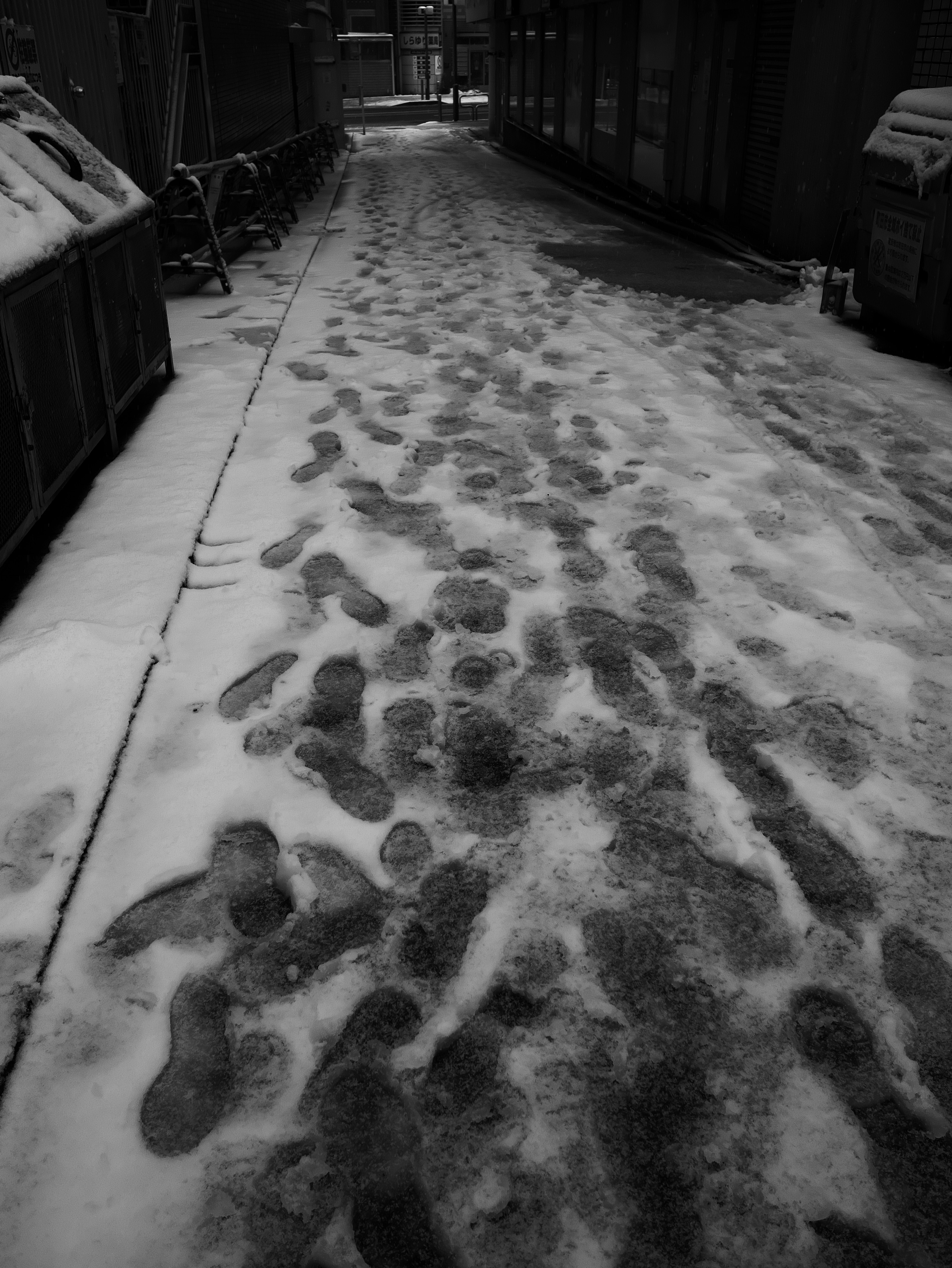 雪の中の足跡が残る狭い通りの風景