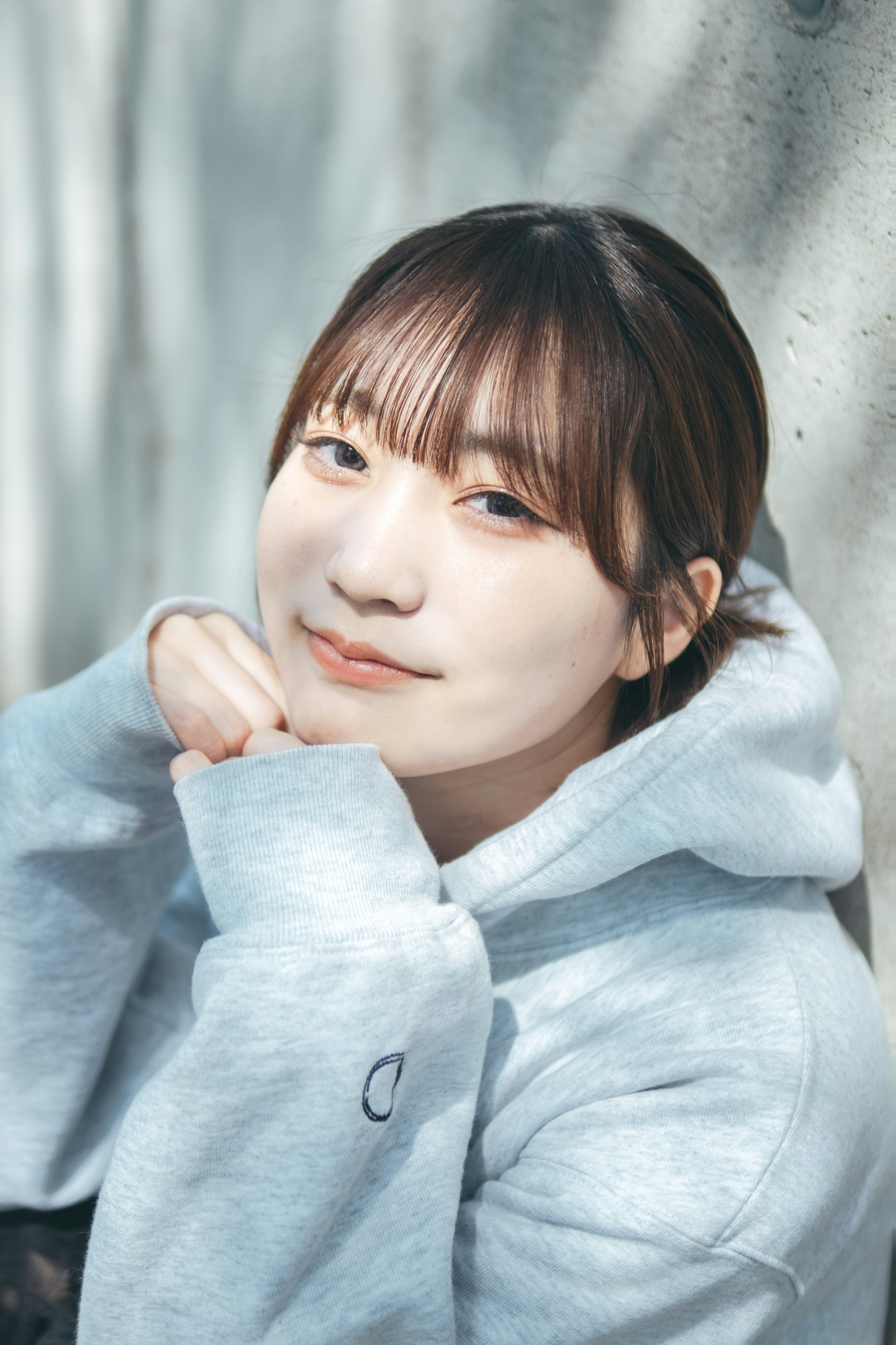 Young woman wearing a gray hoodie smiling softly